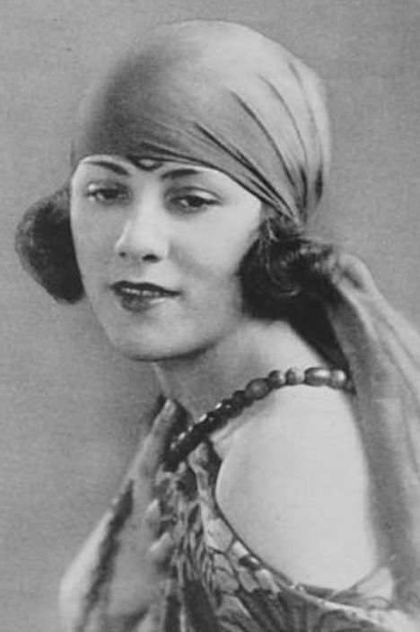 Doris Patston, from a 1925 publication; a young white woman with bobbed dark hair, wearing a head scarf and a costume with bare shoulders