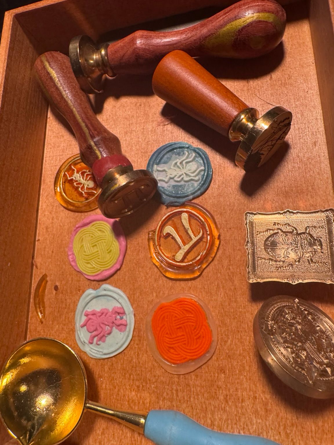 Several wax seals feature ants and mathematical symbols in a wooden box. 