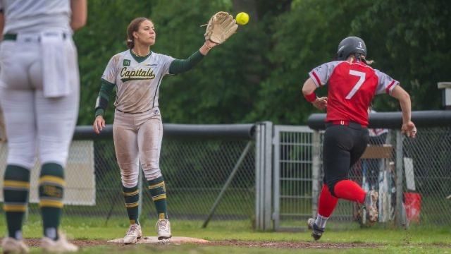 Szene eines Softball-Spiels. Eine Spielerin der Bonn Capitals steht am Base und fängt den ankommenden Ball, bevor die gegnerische Läuferin das Base erreichen kann, sie ist noch ca. einen Meter entfernt