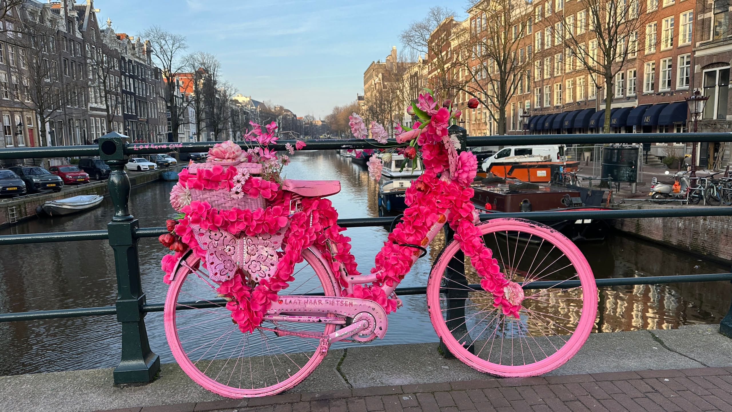 pink bicycle with neon flowers on a bridge over a canal