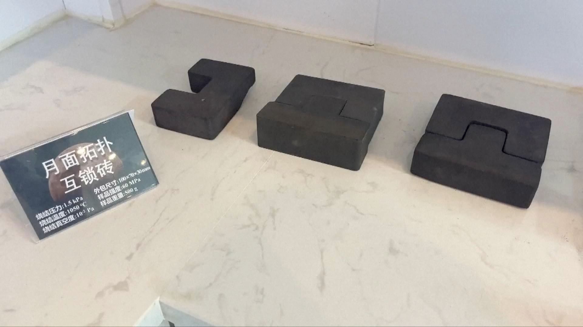 Fotografia di alcuni modelli di mattoni lunare con un cartello in cinese che ne descrive le caratteristiche