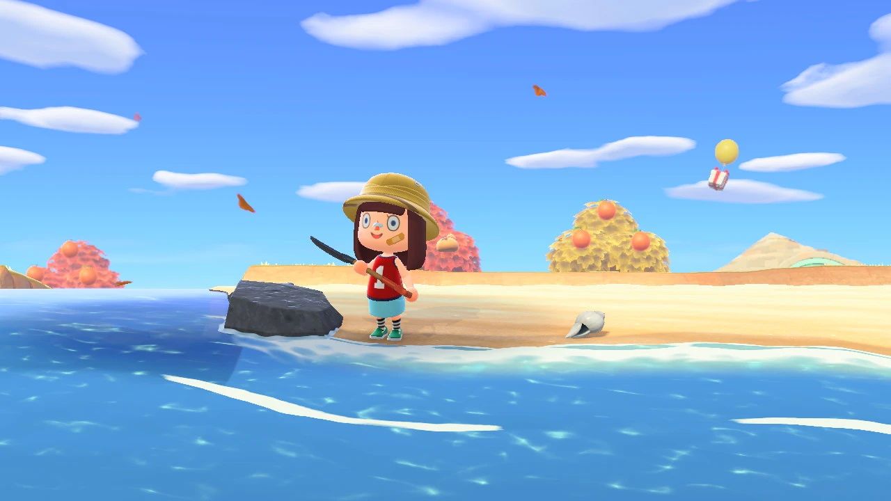 Foto in riva al mare con gli alberi autunnali che si vedono appena dietro, con un palloncino in lontananza e foglie secche che fluttuano.