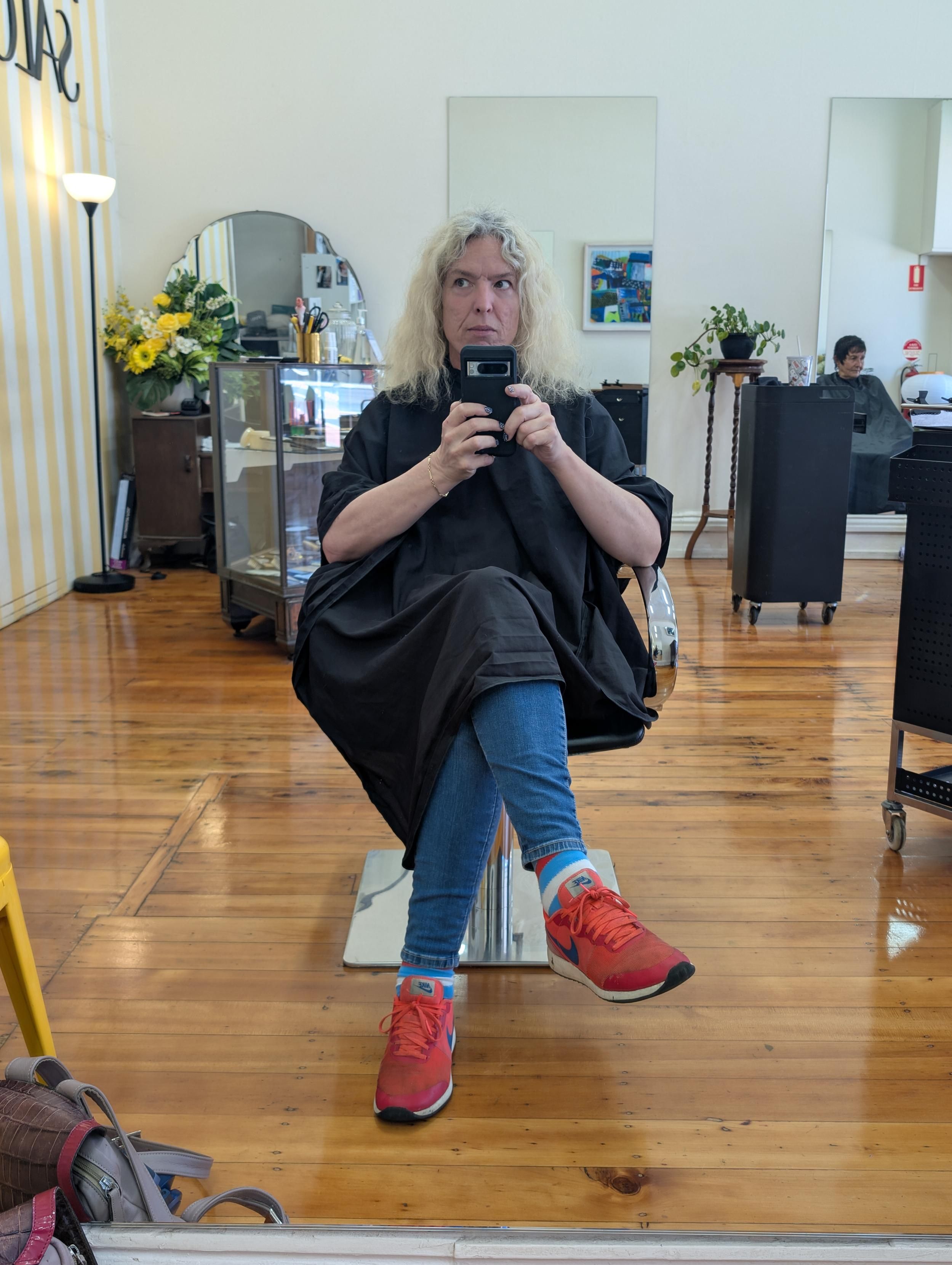 Me in a hairdresser, waiting to get my done, red shoes jeans and a mop of blonde hair
