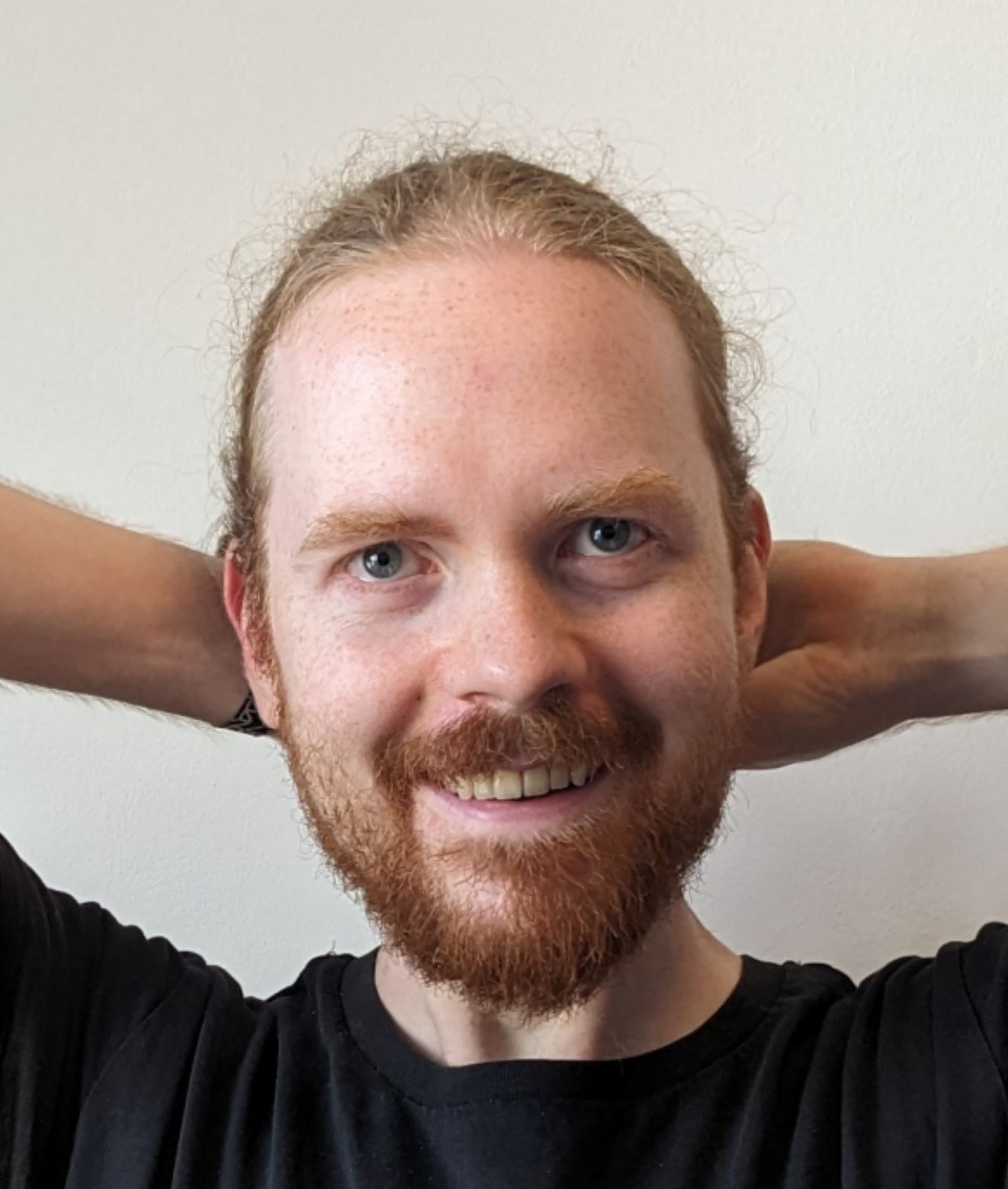 My face is thinner, and my beard is shorter. The photo is taken in front of a white wall.