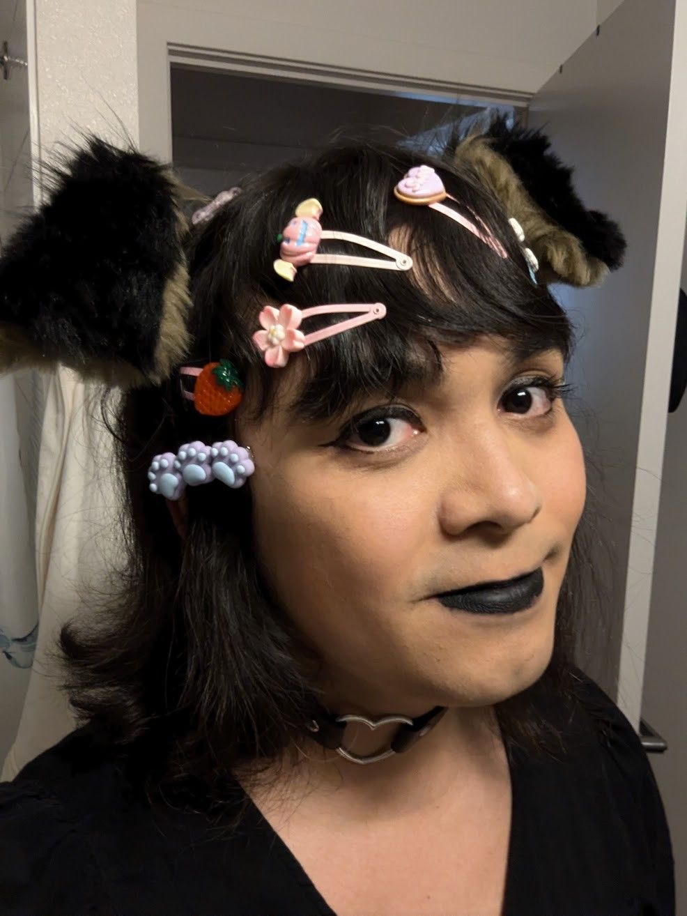 a woman in makeup with dog ears, many hair clips in her short hair, and a choker around her neck