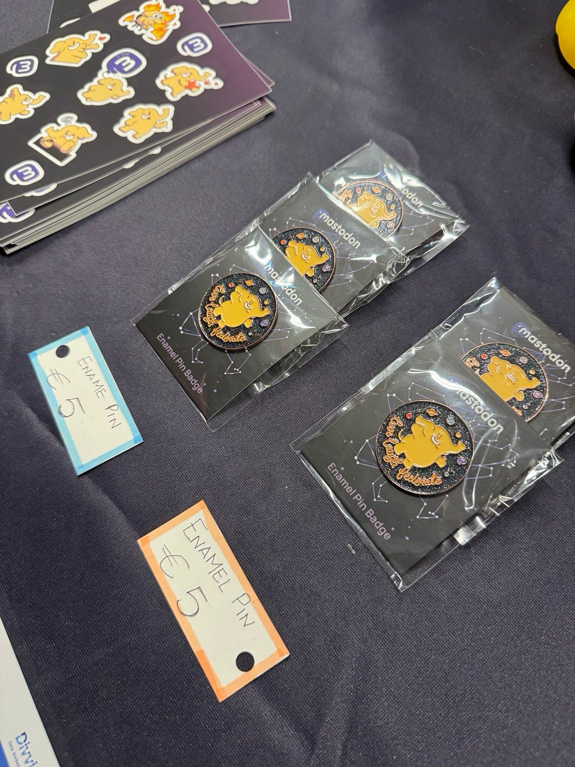 Five beautiful enamel pins featuring the Mastodon mascot, on a table