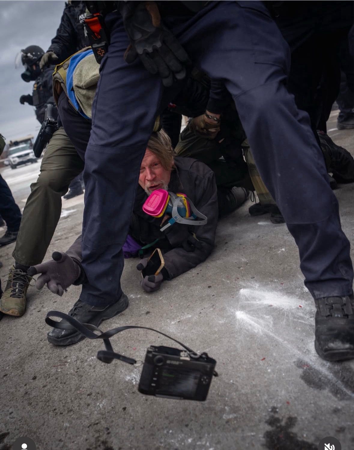 Getty photojournalist John Abernathy is seen face down on ground pinned & surrounded by federal agents. His arm is outstretched & his camera is midair as he tossed it to another photographer so it wouldn't be confiscated. Photo by Pierre Lavie.