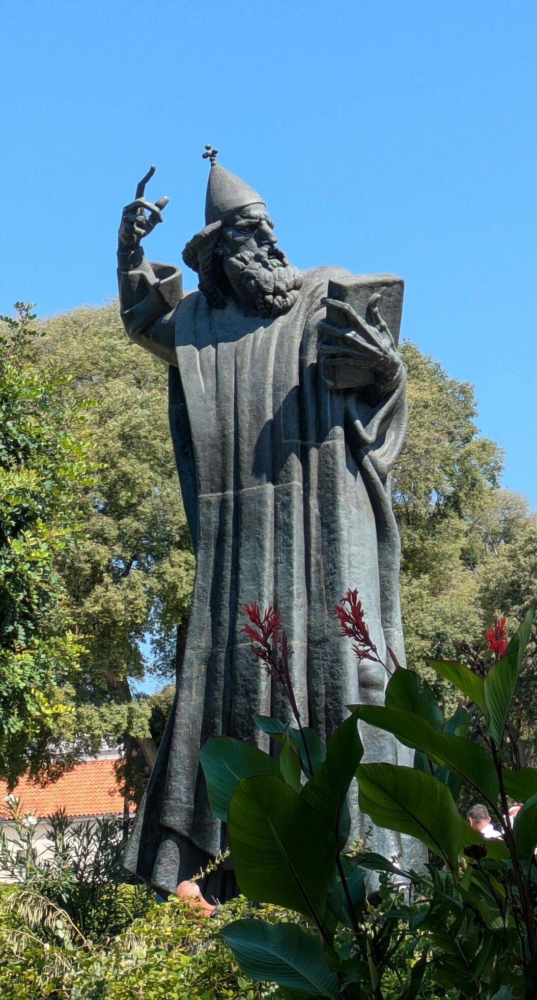 A statue of Saint Grgur of Nim in Split.

The statue is in dark bronze and represents a bearded man dressed in robes, holding a book in his left hand, his right hand raised to the sky, with a finger pointing up. He is looking at the book.

His expression is very stern and he looks like he is going to punish someone or cast divine retributions on unbelievers. This is in contrast with the funny hat on his head, which has a small episcopalian cross on top.