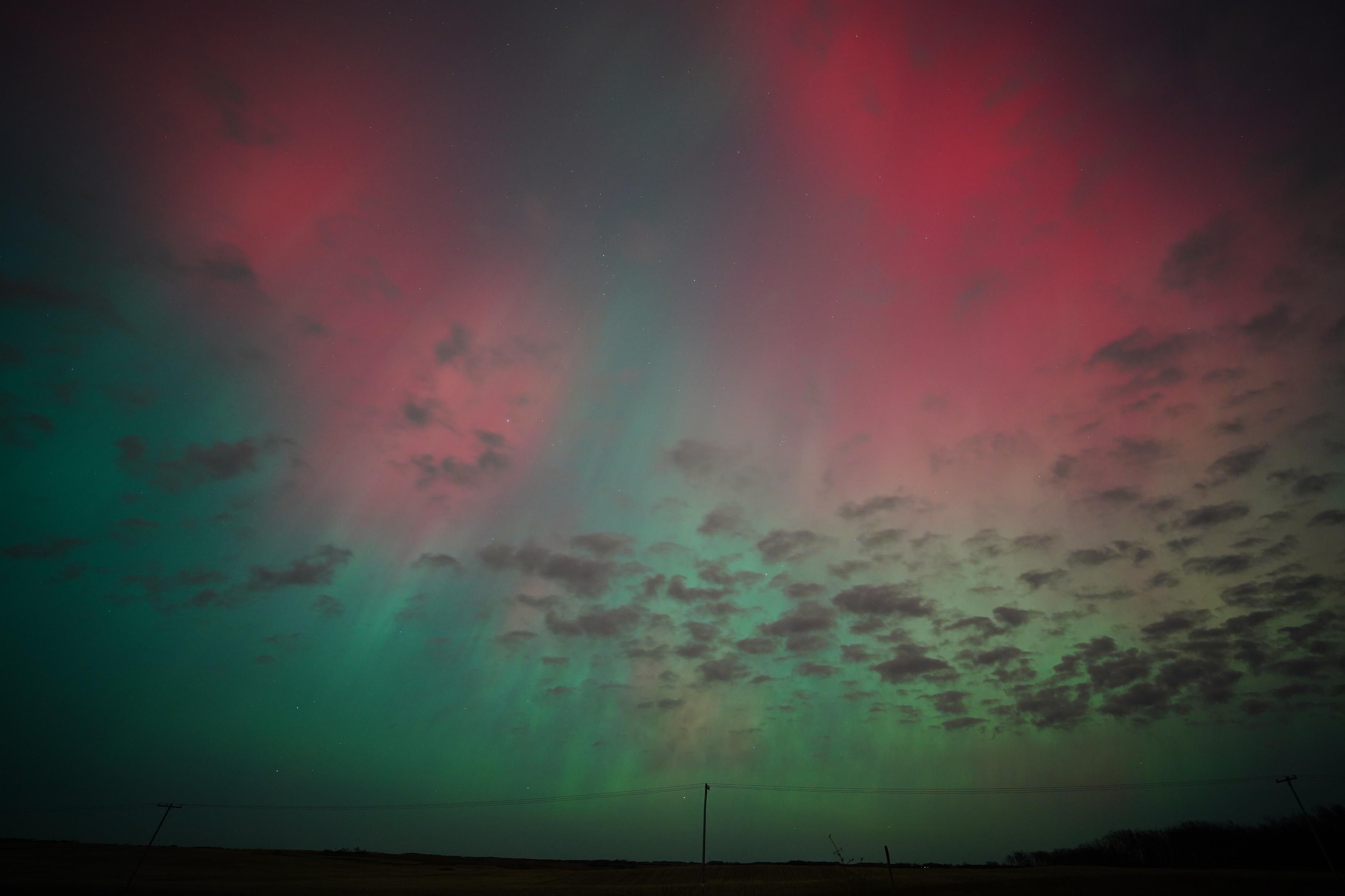 A patch of red auroras on each side of the photo, with green all around.  There are also some small dots of cloud dispersed around the sky, covering up the auroras.