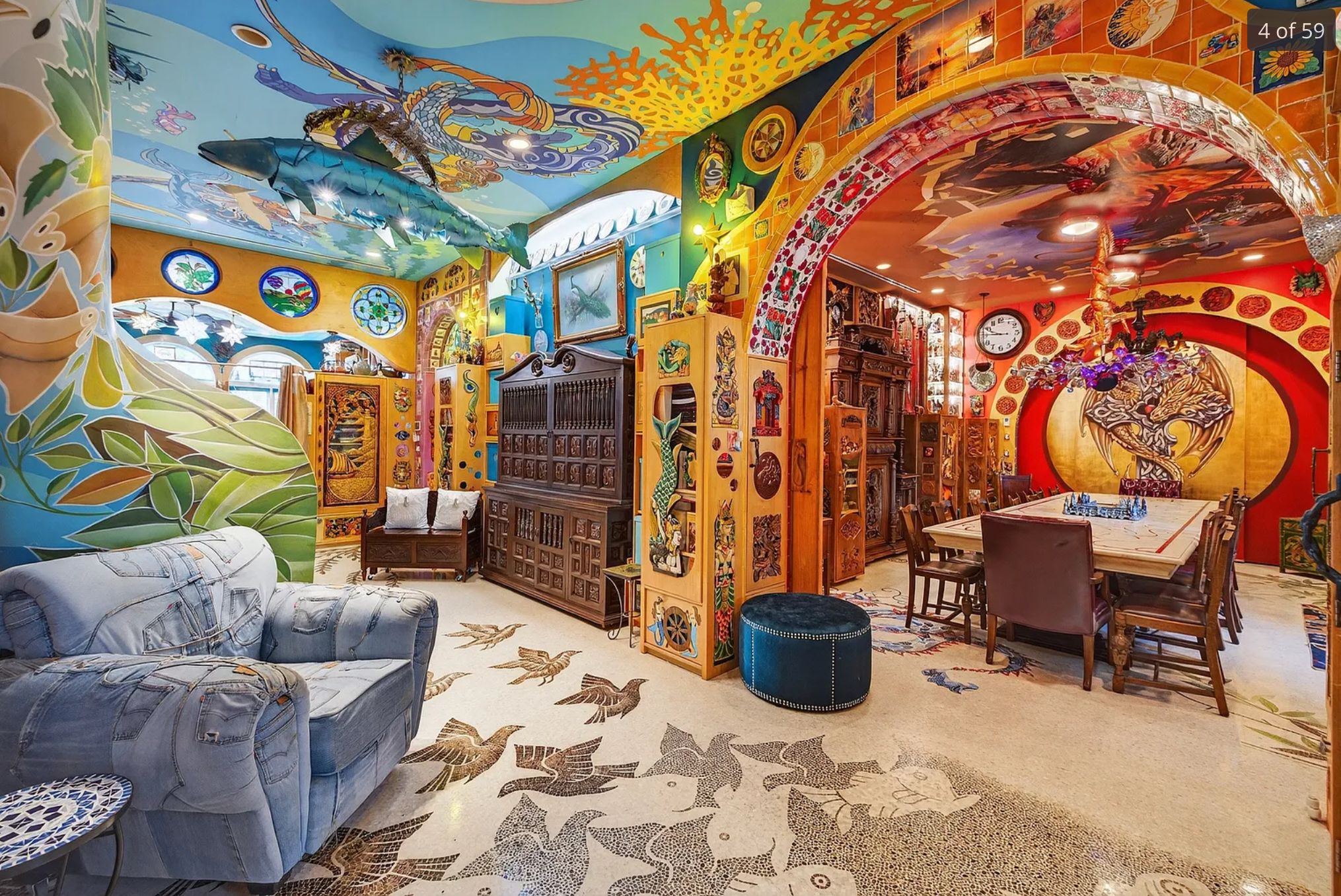 A room with bright neon murals and paint all over the ceiling and walls, it is numerous patterns and images of things like fish and dragons, and then there is a chair made out of old pairs of jeans. 