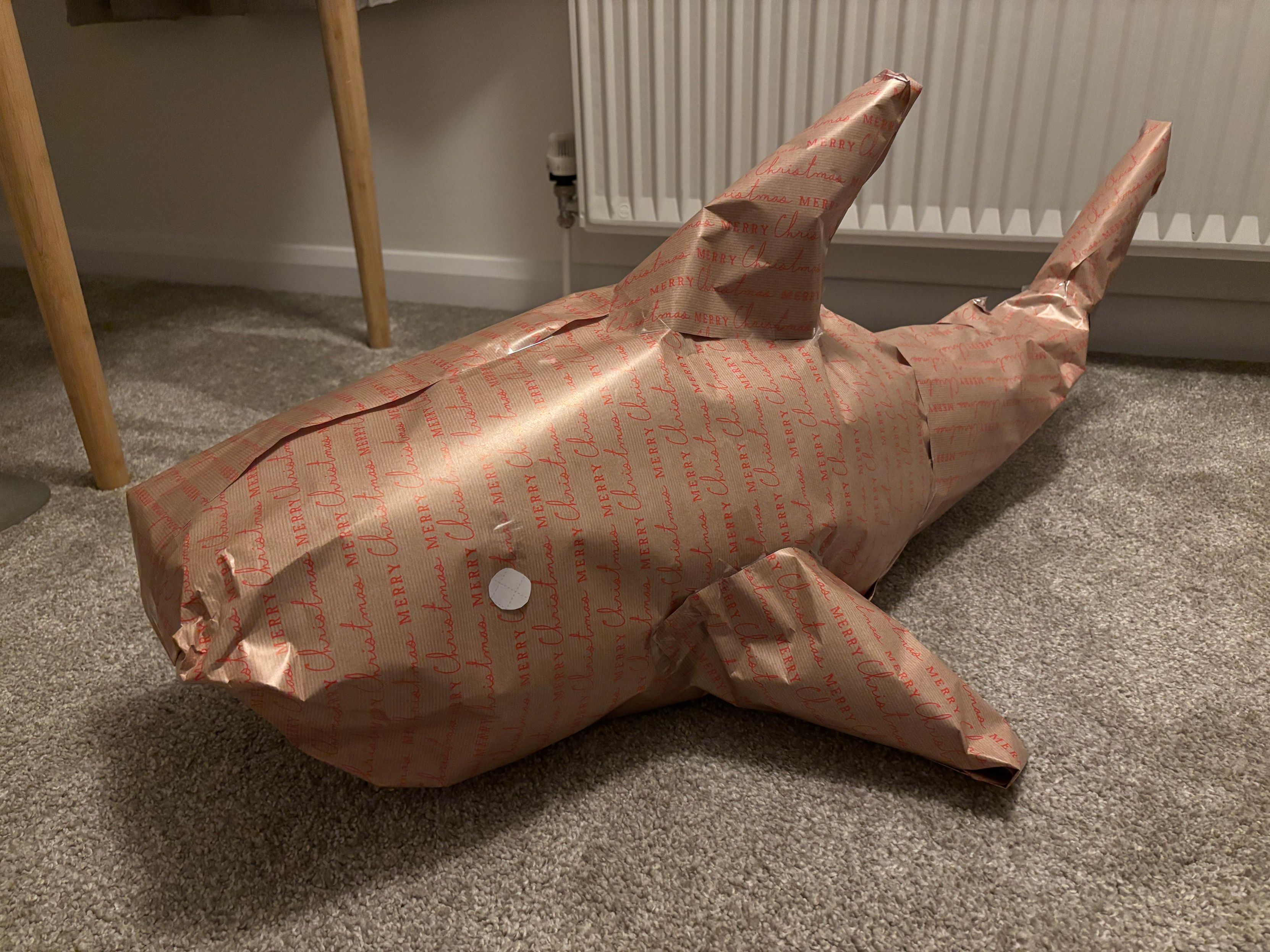 A gift-wrapped Blåhaj, in a very obvious Blåhaj shape.