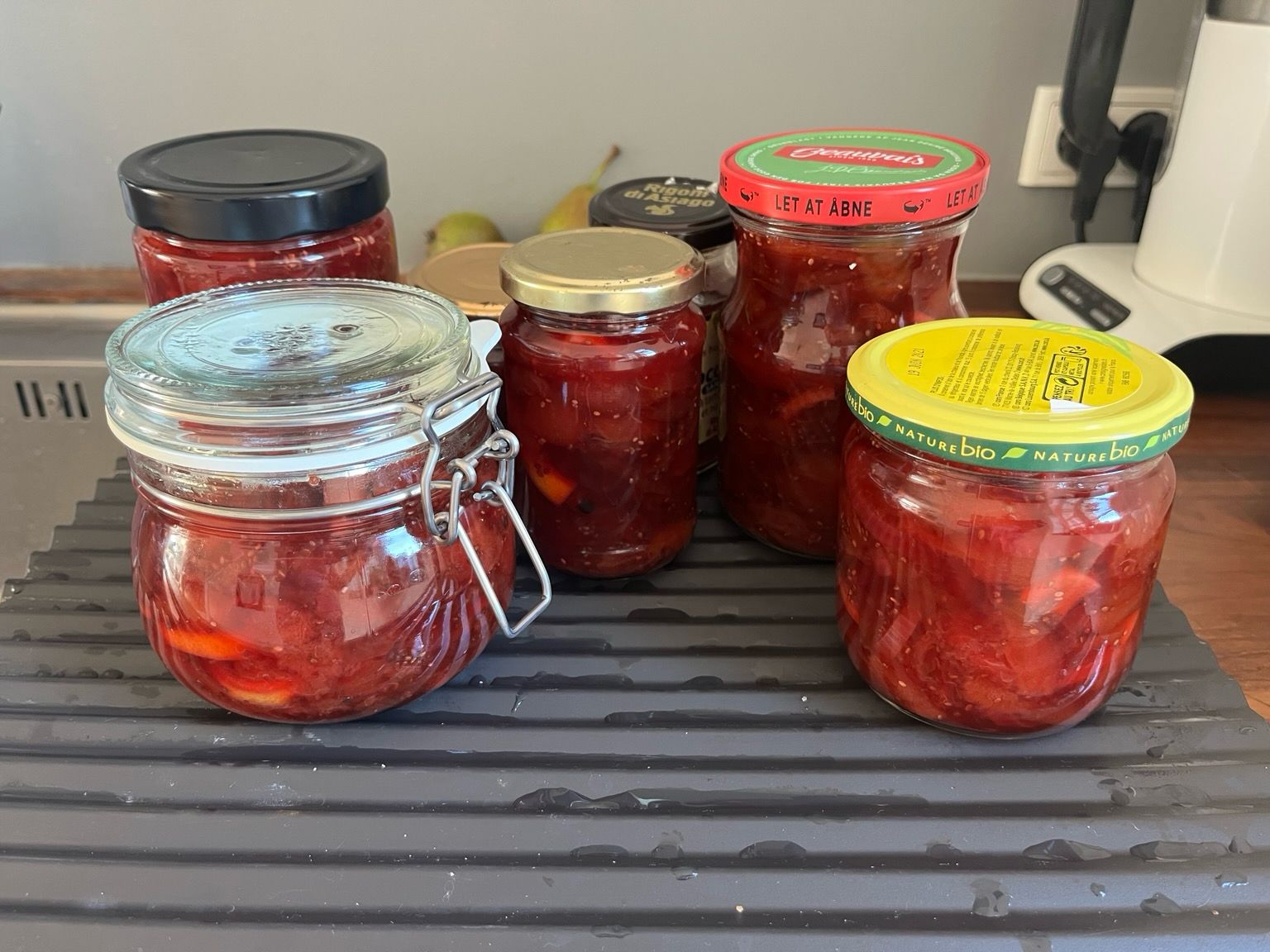 Sort plastikbakke med en blanding omgang glas fyldt med mørkerød blommechutney