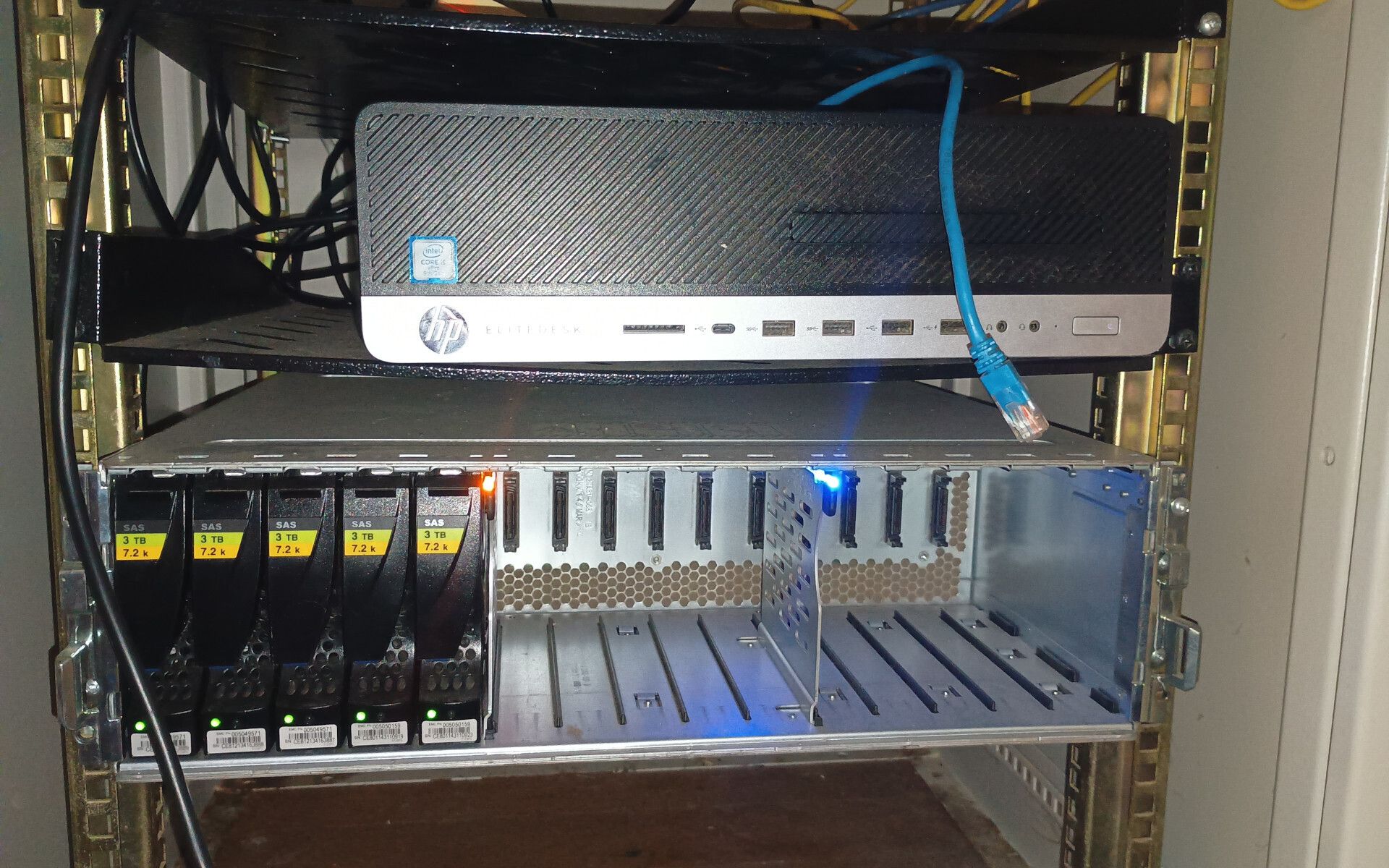 "asakura" - a black and silver HP business desktop, on a rack shelf  above a shiny silver disk array, containing 5 drives labelled "SAS 3TB"