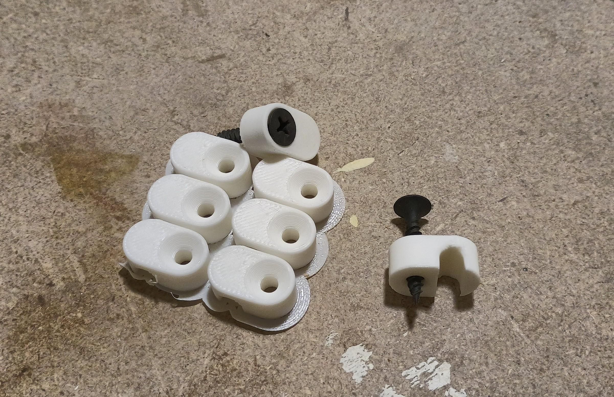 Six freshly painted white plastic clips and two that have screws in them. A short black drywall screw fits very neatly in the clip.