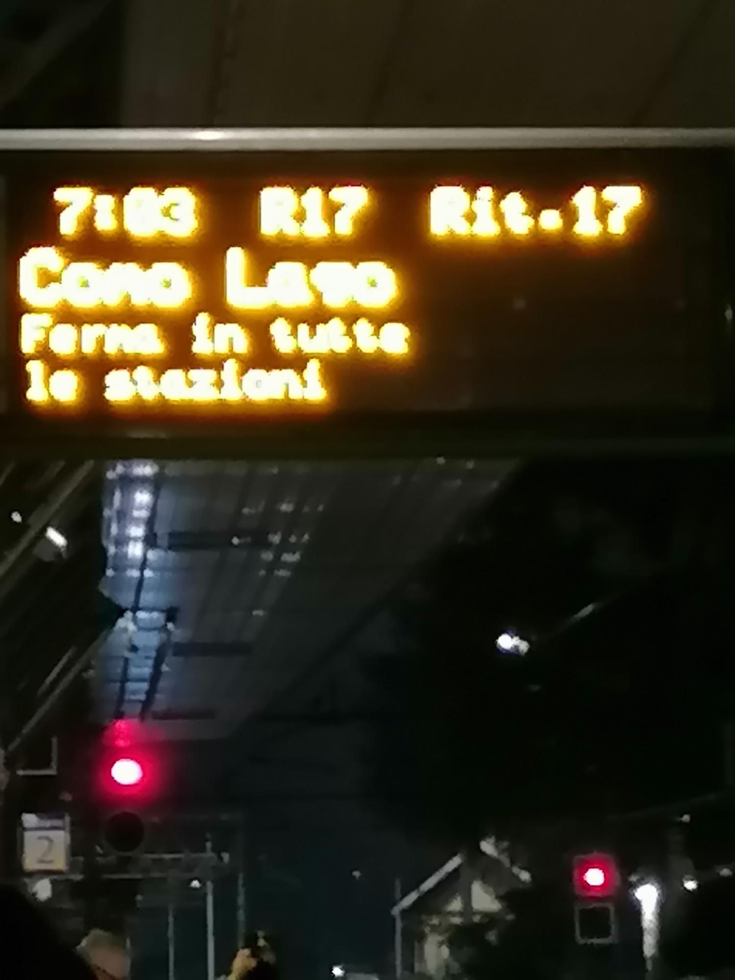 Tabellone sulla banchina, indica 17 minuti di ritardo del treno per Como lago