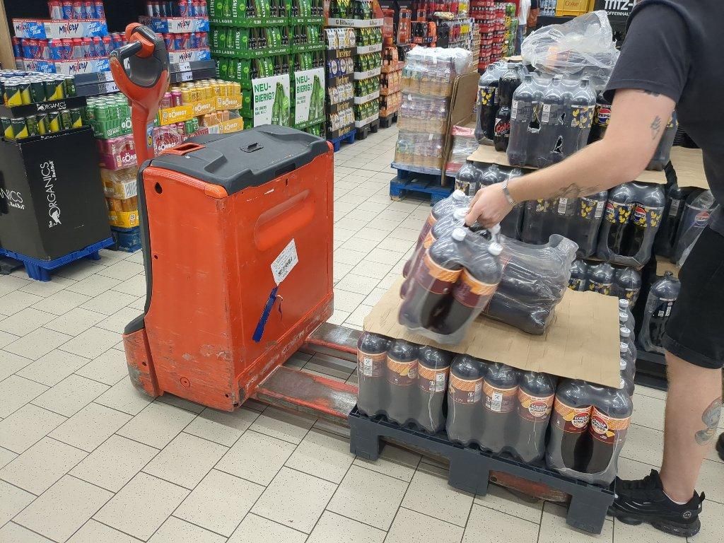 Gang im Kaufland mit Hubwagen mit dickem roten Motor- und Akkublock hinter dem Griffarm