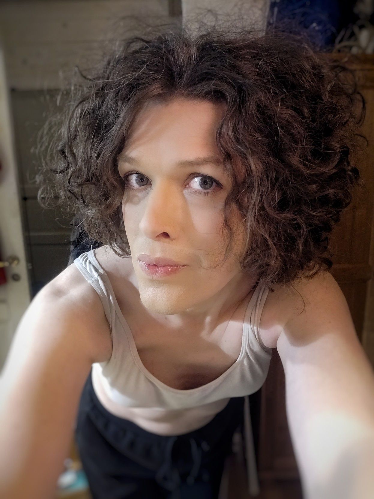 leaning forward towards to camera revealing some white bra cleavage, head turned to the side but my eyes looking into the camera, my mouth pursed