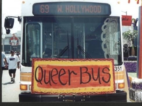 an LACMTA bus with a large hand painted sign on the front bike rack reading "queer bus"