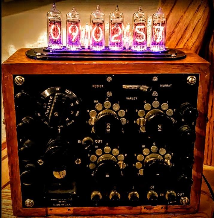 The image shows a vintage-style electronic device with a wooden casing. At the top, there are six glass tubes, each displaying a digit in a glowing purple hue, forming the time "09:02:58." Below the tubes, the front panel features a variety of knobs and dials. On the left, there is a large circular dial labeled "MULTIPLIER" with a scale from 1 to 10,000. In the center, there are two sets of rotary knobs labeled "RESIST." and "VARLEY," with scales ranging from 0 to 1000. The right side has additional knobs and switches, with labels such as "MURRAY" and "IN OUT." The device is labeled "PHILADELPHIA 13584 MADE IN U.S.A." at the bottom. The overall design suggests a piece of retro electronic equipment, possibly a clock or timer.

Provided by @altbot, generated privately and locally using Ovis2-8B

🌱 Energy used: 0.204 Wh