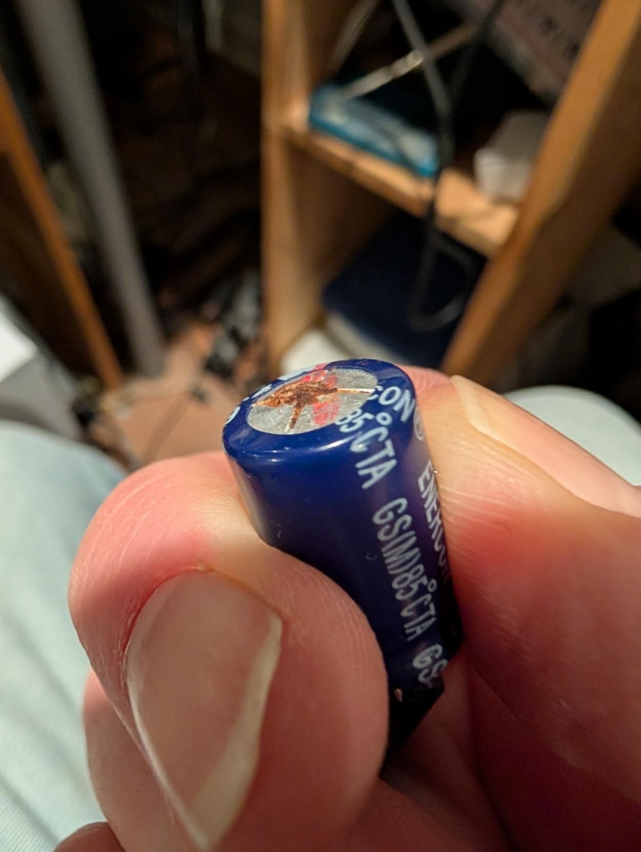 A 4700uF electrolytic capacitor that is domed and leaking electrolyte.