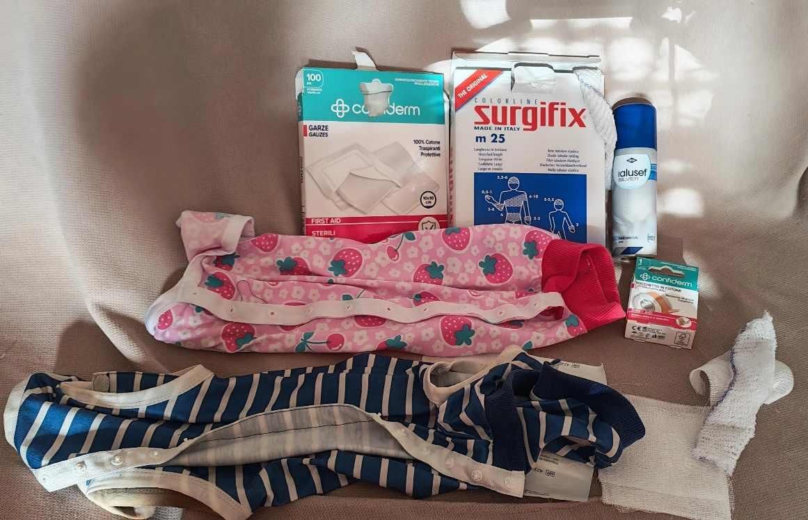 Vari prodotti medici tra cui garze, disinfettante e due tutine post operatorie