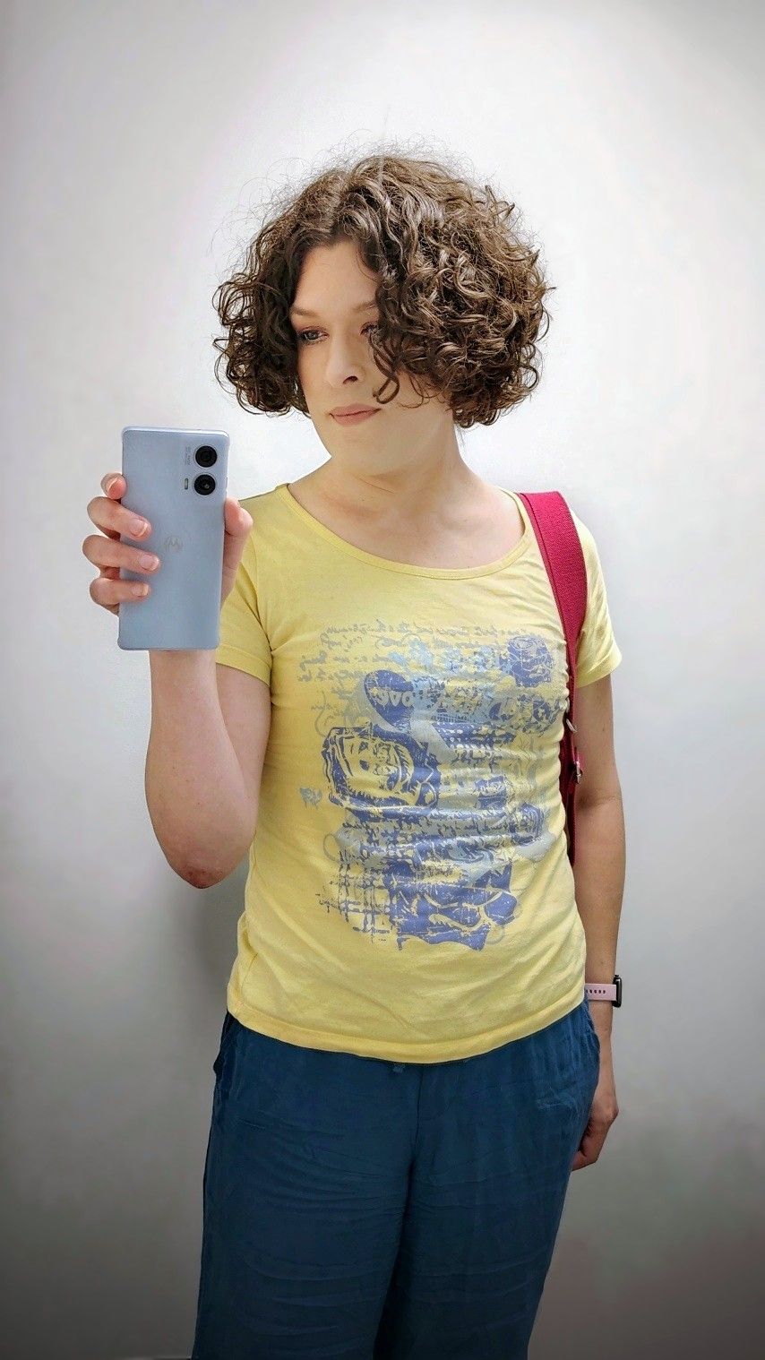 mirror selfie. I'm looking at my phone. I'm wearing blue pants and a yellow top with a messy blue and turquoise print.