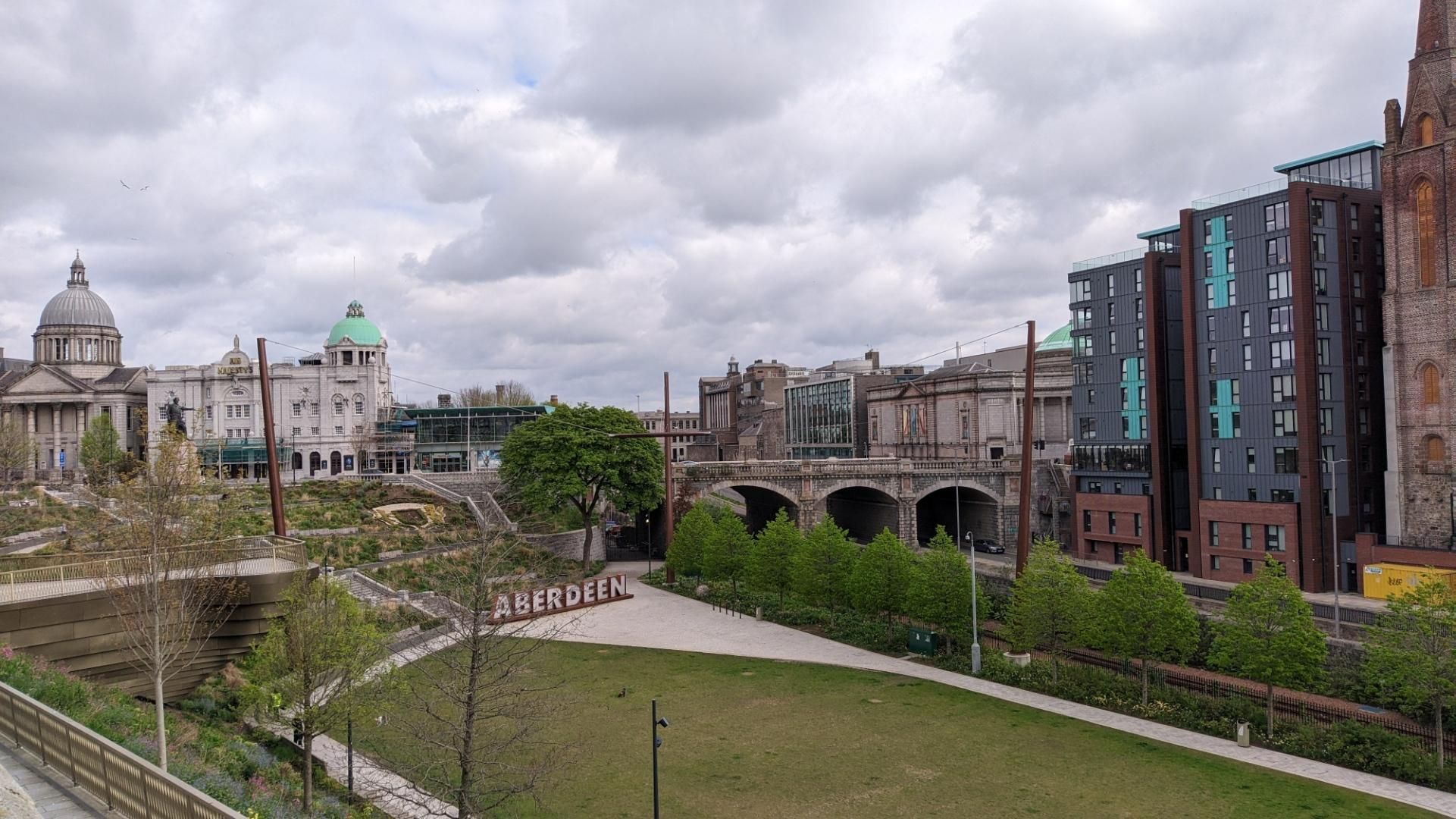 Union terrace gardens in Aberdeen, modern buildings on the right with bridge over railway tracks before that and old buildings on the left