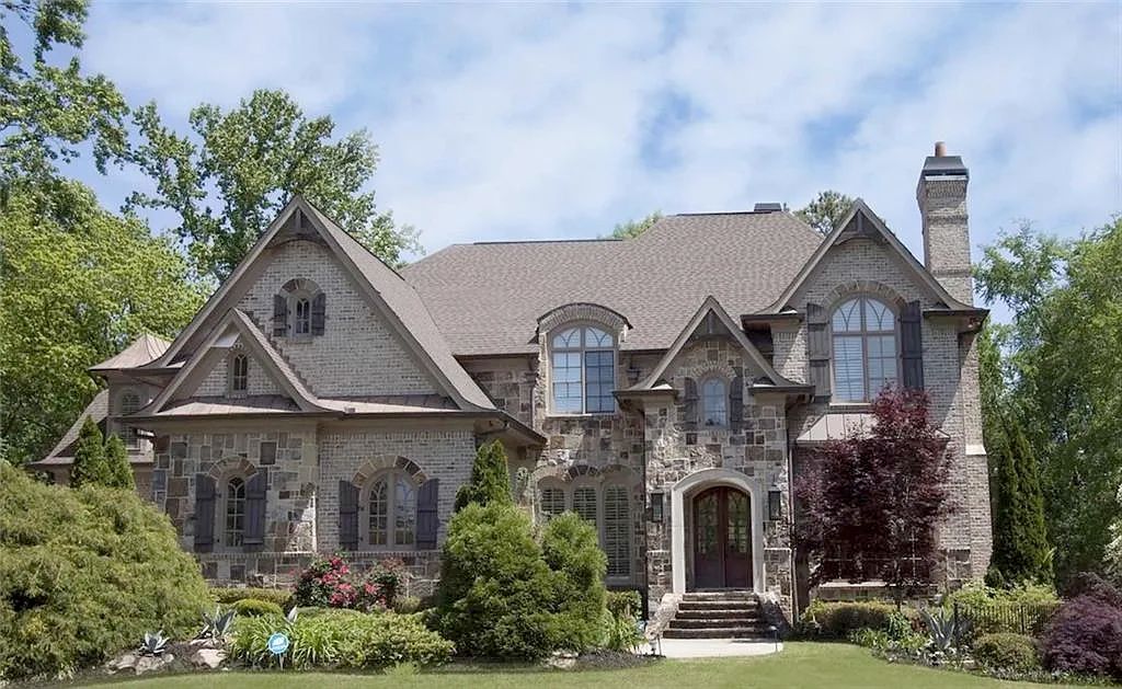 A very large beige house with a facade that is a mix of brick and stone, and curved windows. There is nothing particularly interesting about it. 