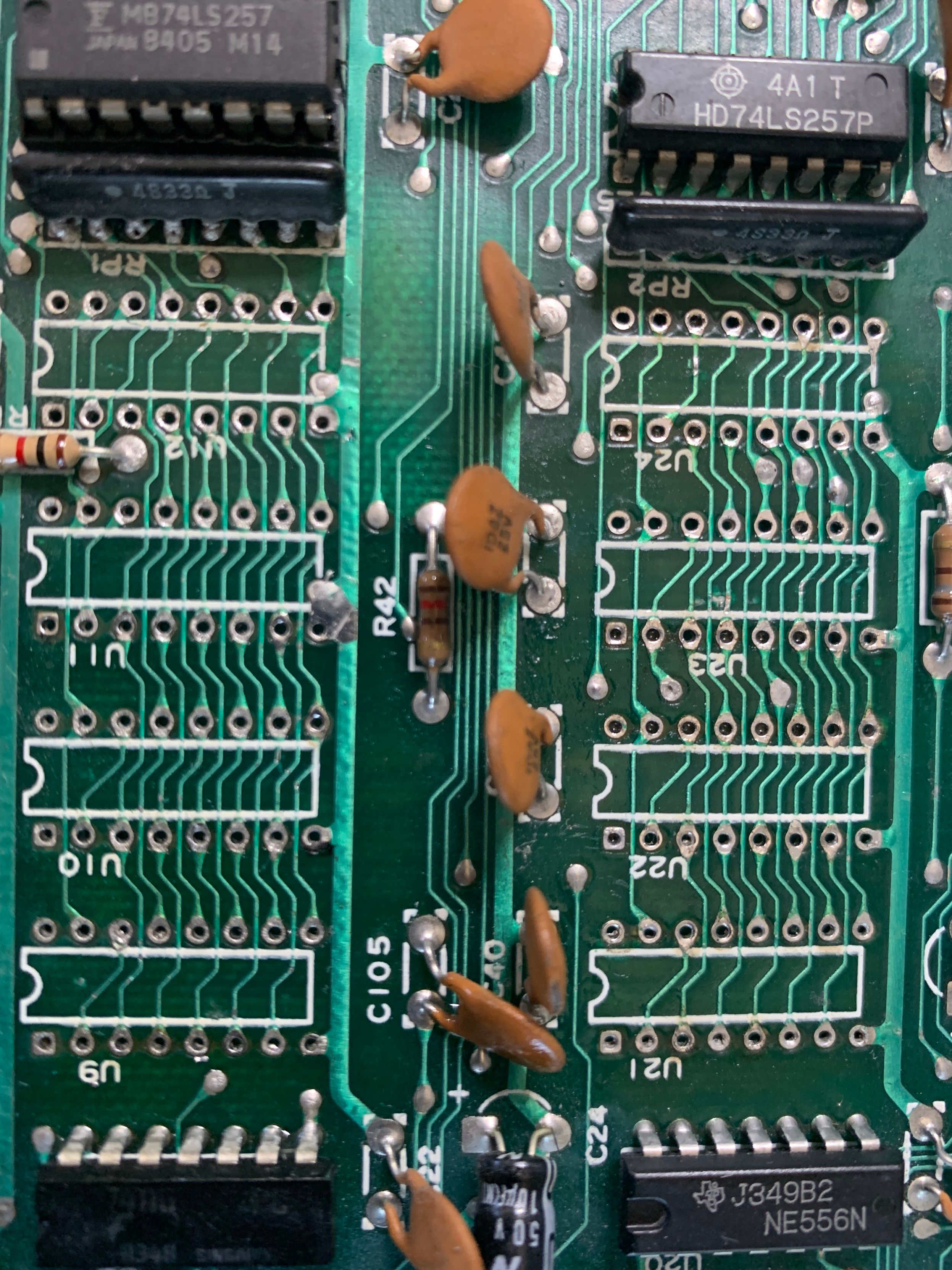 Top view of the sockets for RAM on C64 main board after desoldering all ram from the board. board has been cleaned and the through hole connectors have been opened again.  U21-U24 and U9-U12 are almost ready for sockets.  Green circuit board with white lettering.