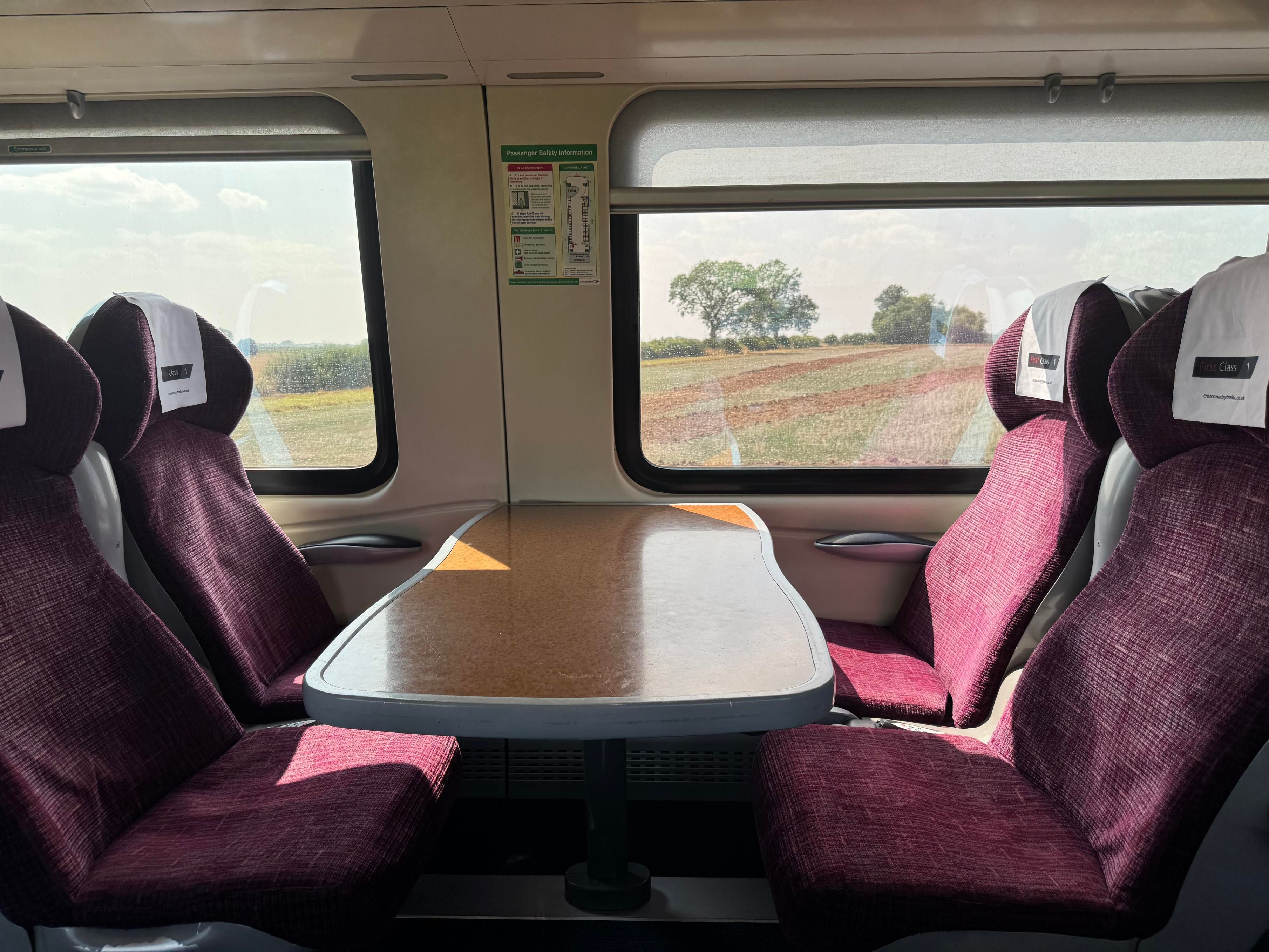 Two sets of two facing seats in the first class coach in this class 220. You can see how badly staggered the seats are compared to the windows. The structural part of the train is off-centre on the table, blocking the view for the people on the left hand side of this photo.