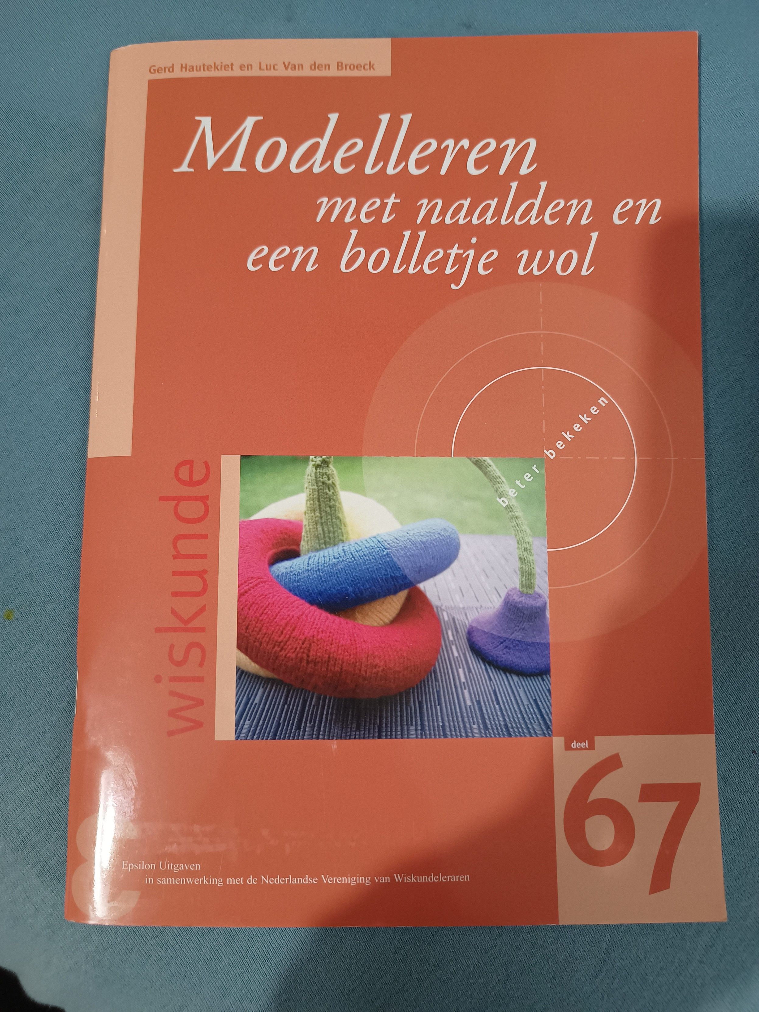 An orange booklet with a picture of some knitted shapes on the cover. The text on the cover says:

Gerd Hautekiet ennLuc Van den Broeck
Modelleren met naalden en een bolletje wol
Beter bekeken
wiskunde
Epsilon Uitgaven in samenwerking met de Nederlandse Vereniging van Wiskundeleraren
deel 67