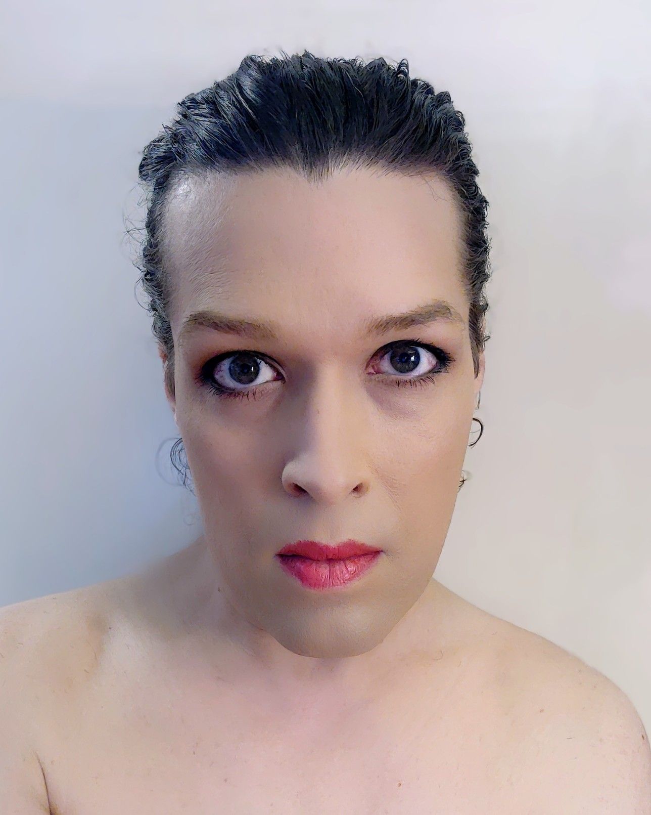 selfie in makeup with my hair pulled back and wearing no shirt. looking serious