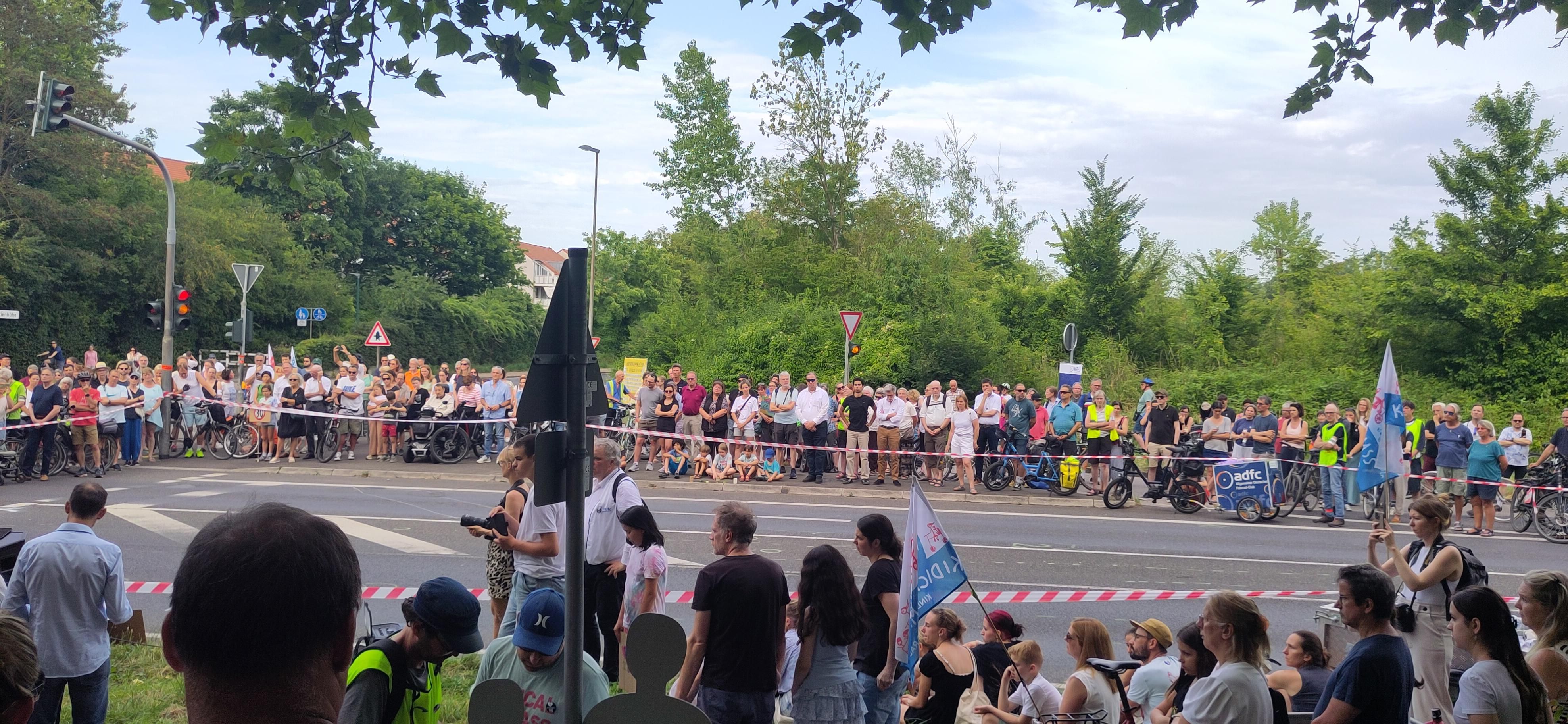 Mahnwache. Viele Menschen stehen um einen abgesperrten Bereich einer Straße herum, wo sich das Unglück ereignet hatte.