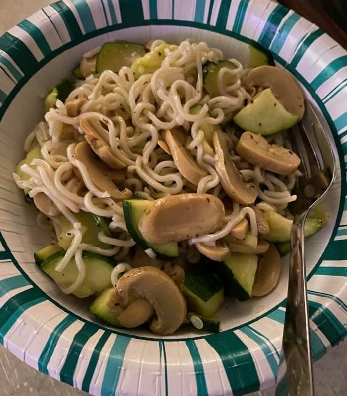 close-up of ramen noodles with sliced mushrooms and zucchini chunks in a bowl