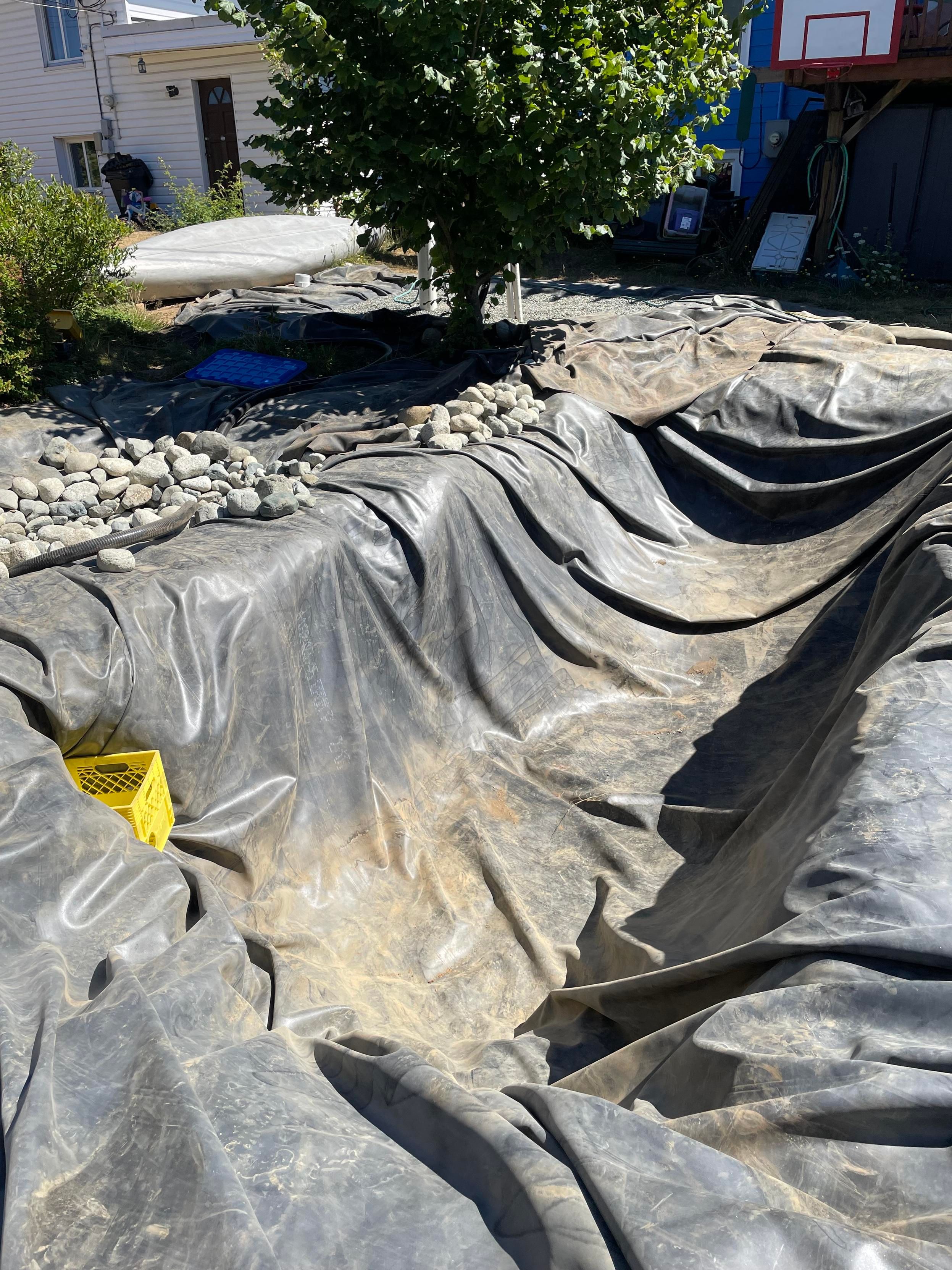 The liner is pulled back over and set in on the near end with the yellow basket but the far end is still stretched over and not set into the hole properly. It is all in full sun. so hot.