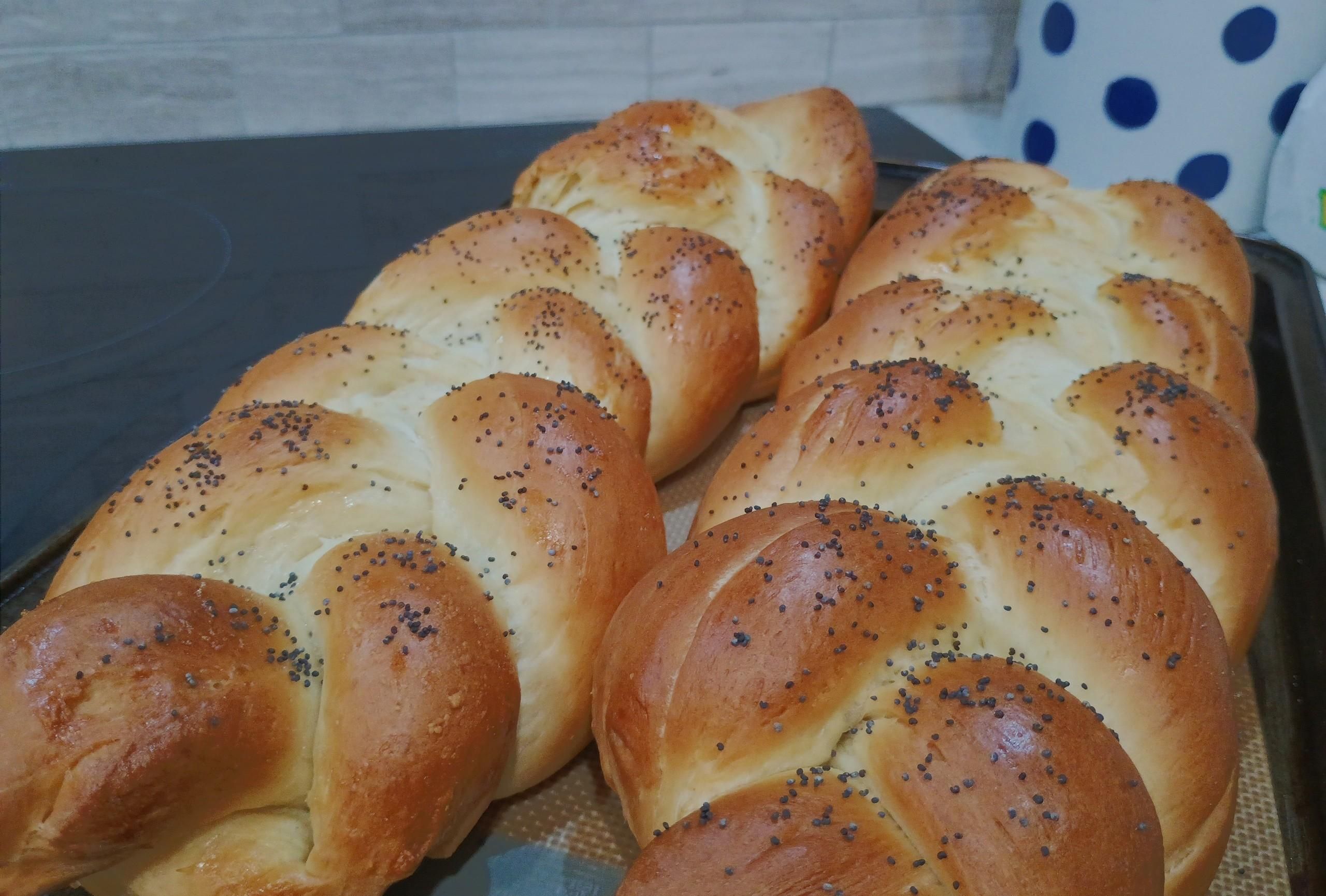 Two braided challah loaves are brown with light inner parts of the braid, and a sprinkle of poppyseed over them. 

Intending to give one to friends, so I guess the slightly unkempt one is to be destroyed at home with my chompers.