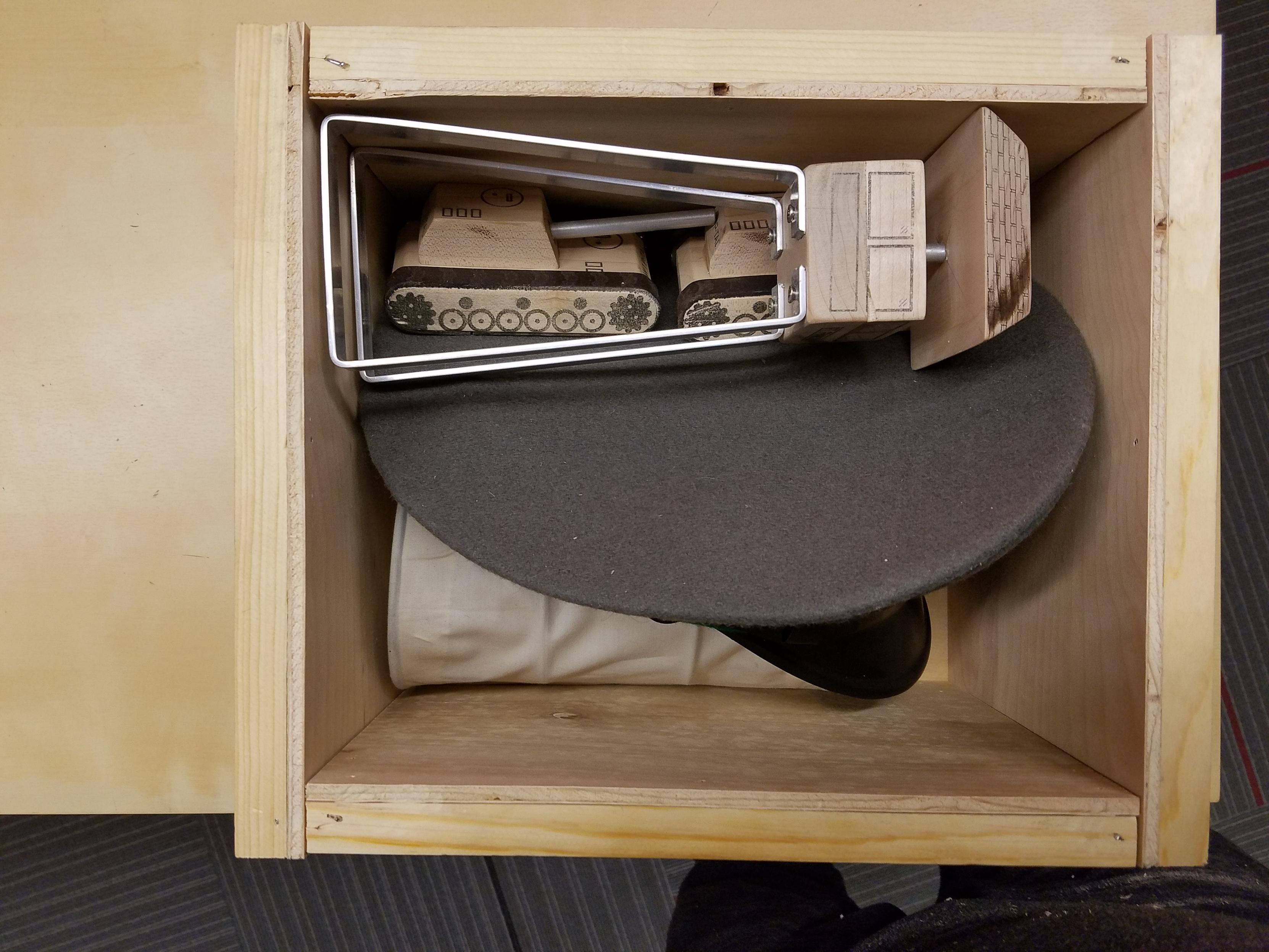 The top of the crate opened so that the contents can be seen. A General's hat and several small plywood figures.