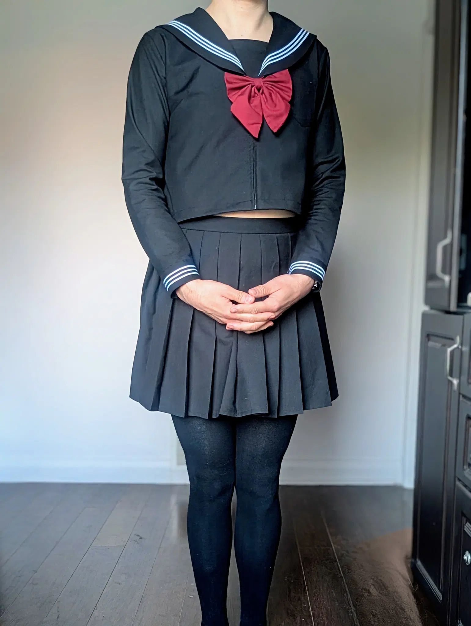 Standing with a cute innocent pose in a black Japanese schoolgirl outfit and thigh high socks and red bow. 
Could I really be as innocent as I look? 