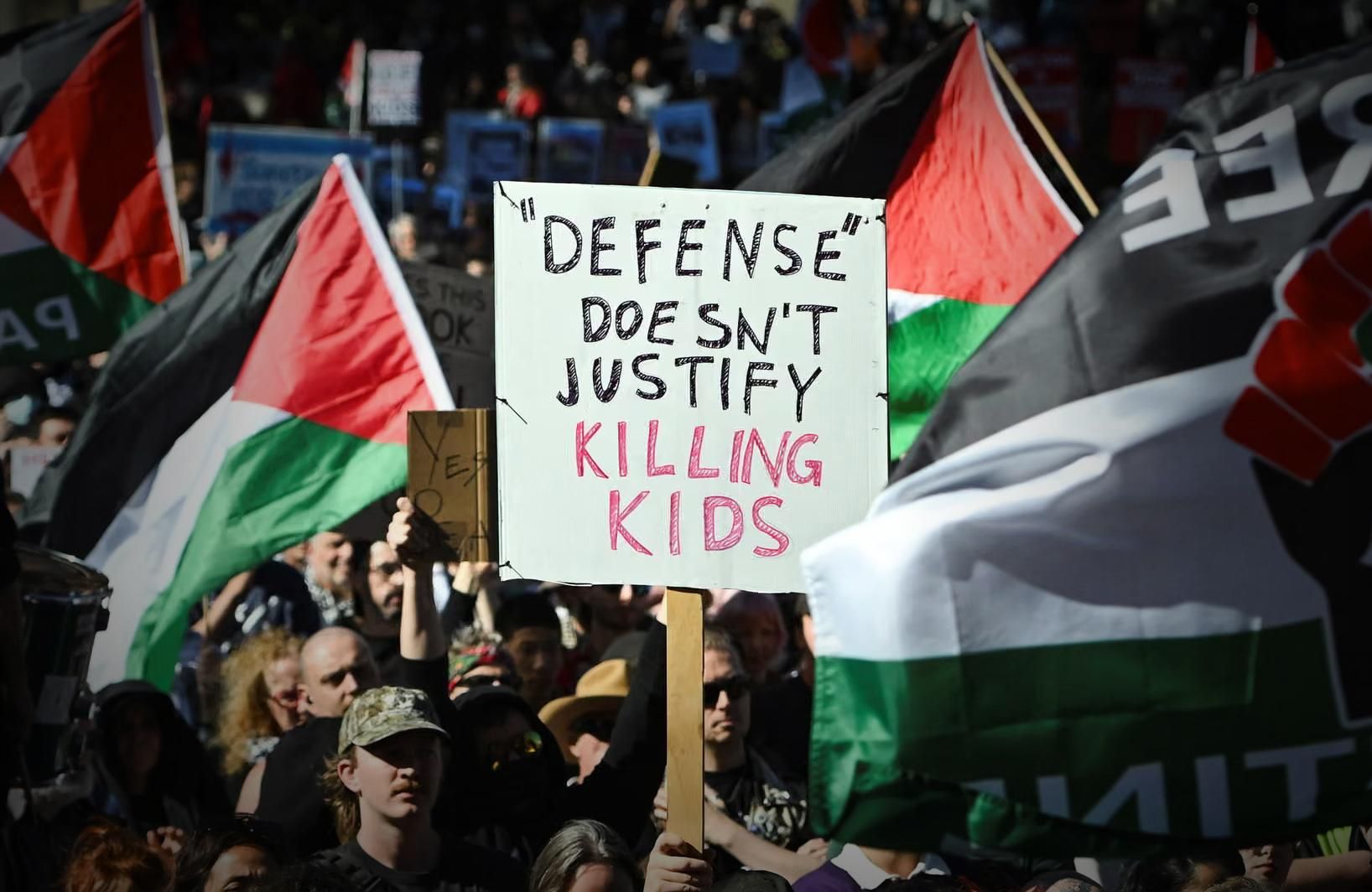 Protestors in Melbourne today holding a sign which reads "Defense" doesn't justify killing kids
