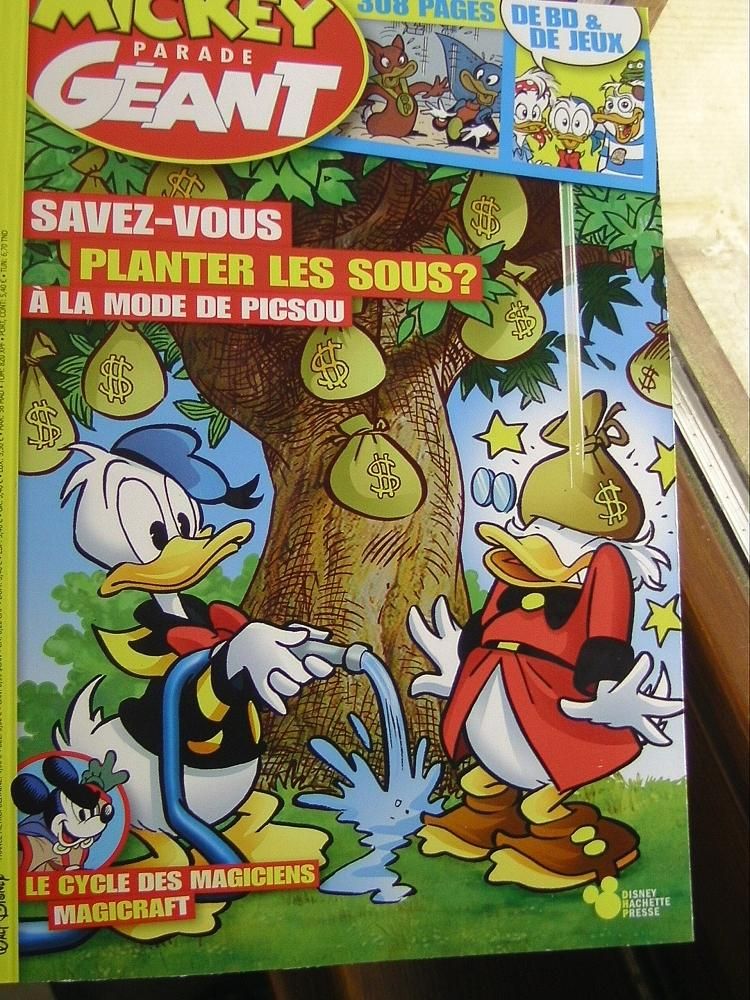 French Donald Duck book. Cover: Donald waters a tree, instead of fruits there are sacks full of dollars. Scrooge stands under the tree, a big sack is falling on his head.