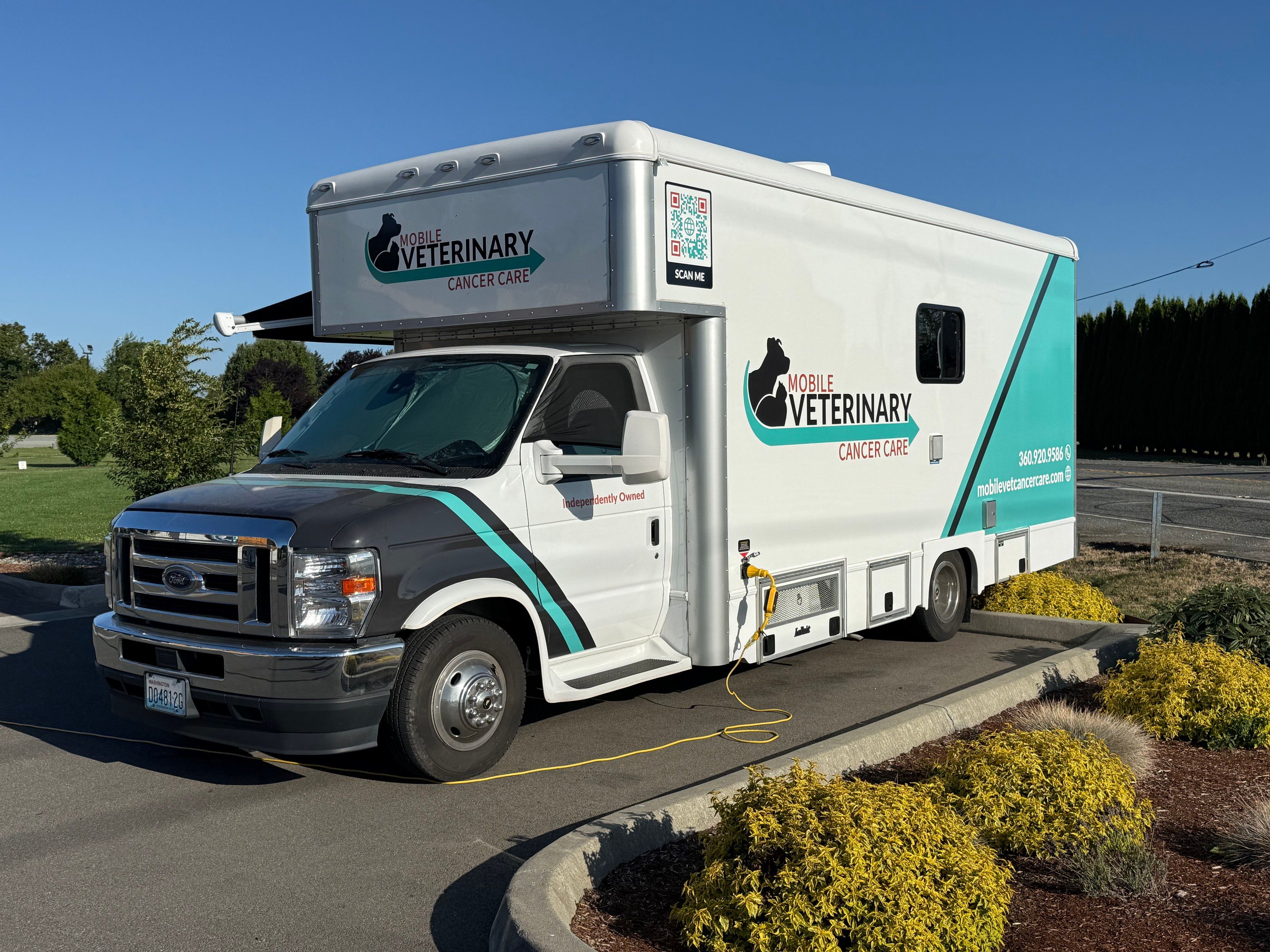 An ambulance-style vehicle. Logo on the side of a car and dog. Text says "Mobile Veterinary Cancer Care".