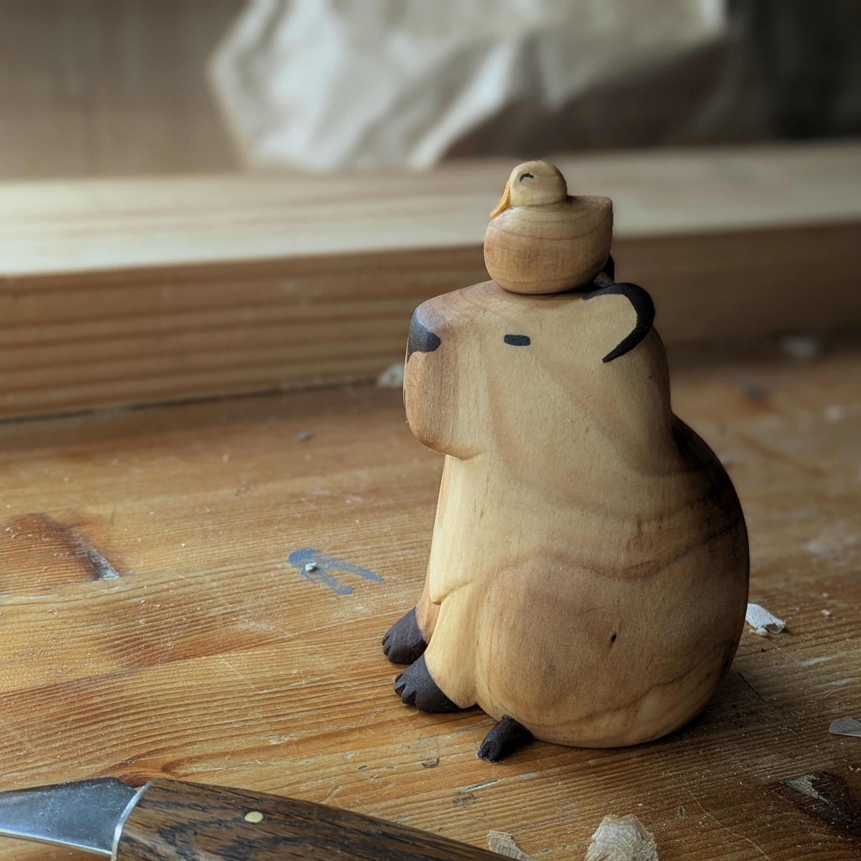 Woodcarved plump capybara with a round duck on its head