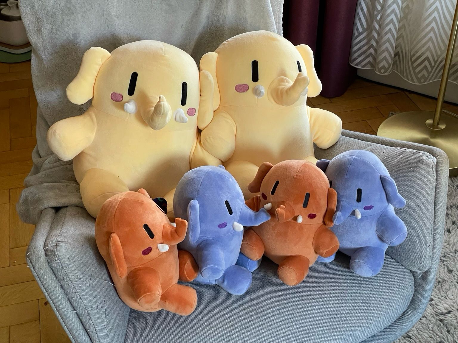 Two large Mastodon stuffed toys in beige color, and 4 little Mastodon stuffed toys, two apricot colored, and two blue.