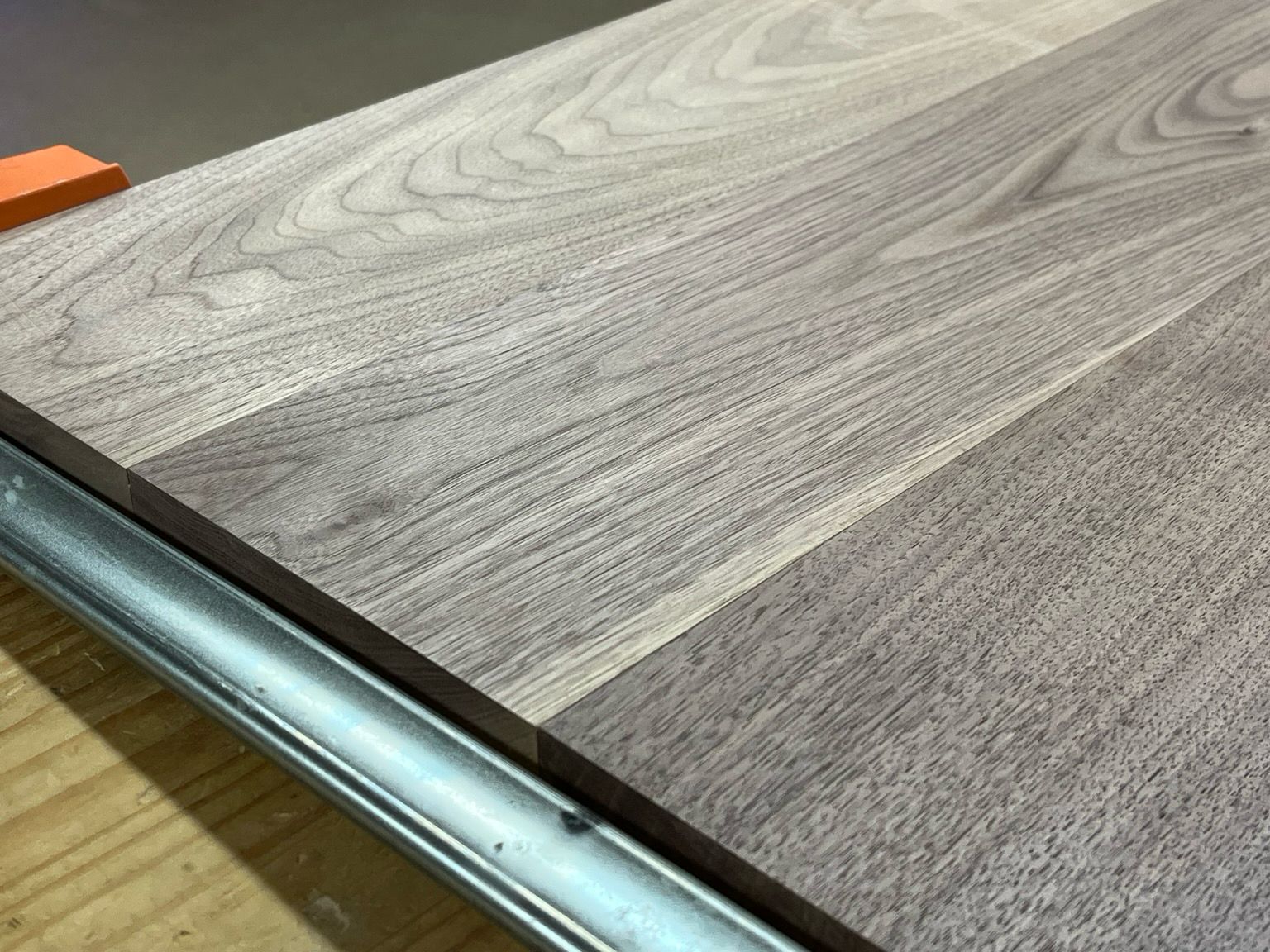 A close up of several walnut boards clamped together on their edges with no gaps.