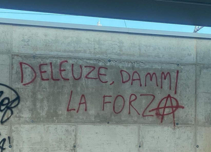 Foto di una scritta rossa, spray su muro: "DELEUZE, DAMMI LA FORZⒶ", 