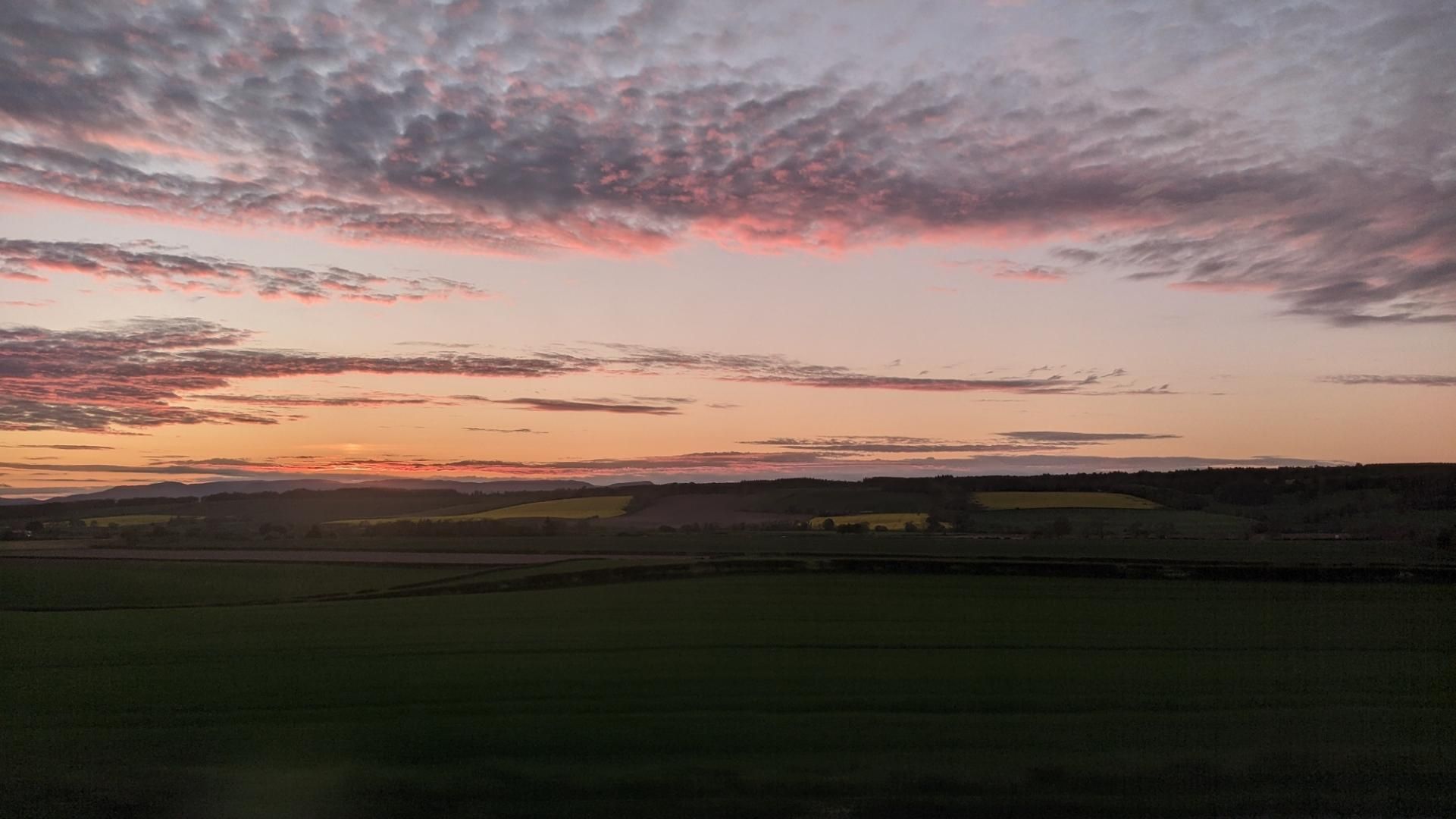 Sunset over fields with a few clouds