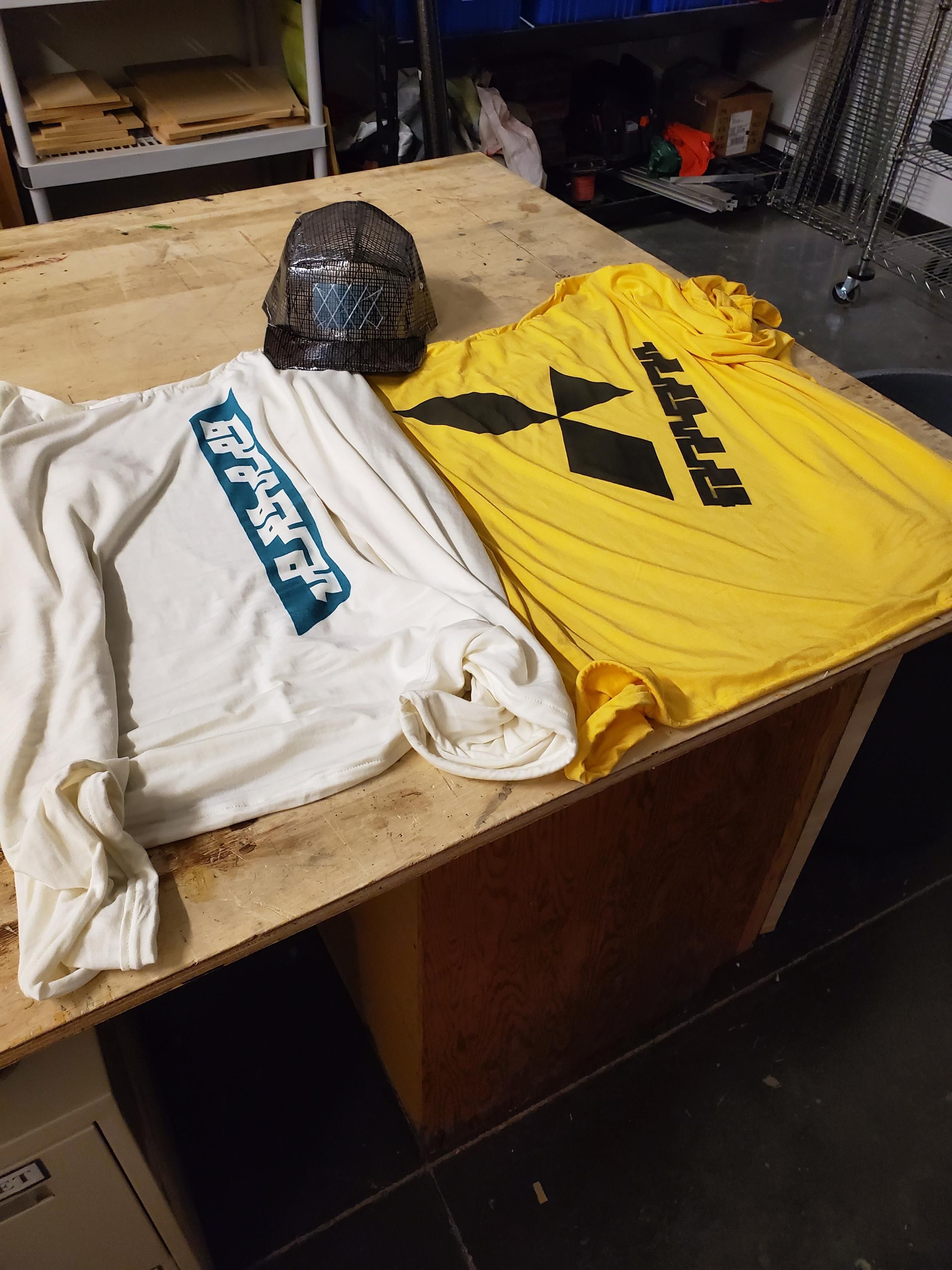 Two shirts with logo prints and a 5 panel hat made from sail polymer