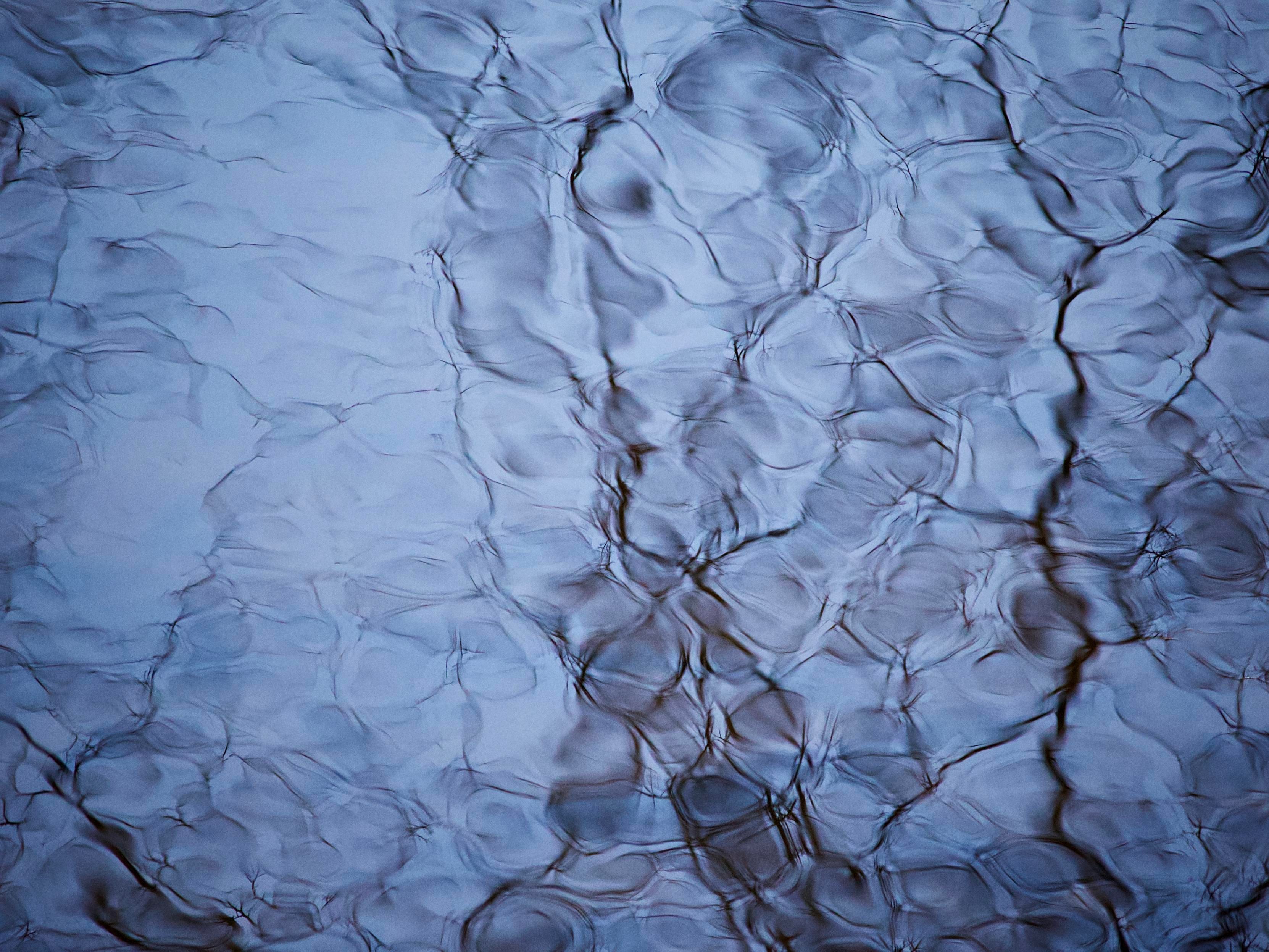 Ripples and reflections of the clear blue sky in the calmer pools on a fast-moving stream create beautiful shapes and textures when low winter sunlight catches the surface of the water