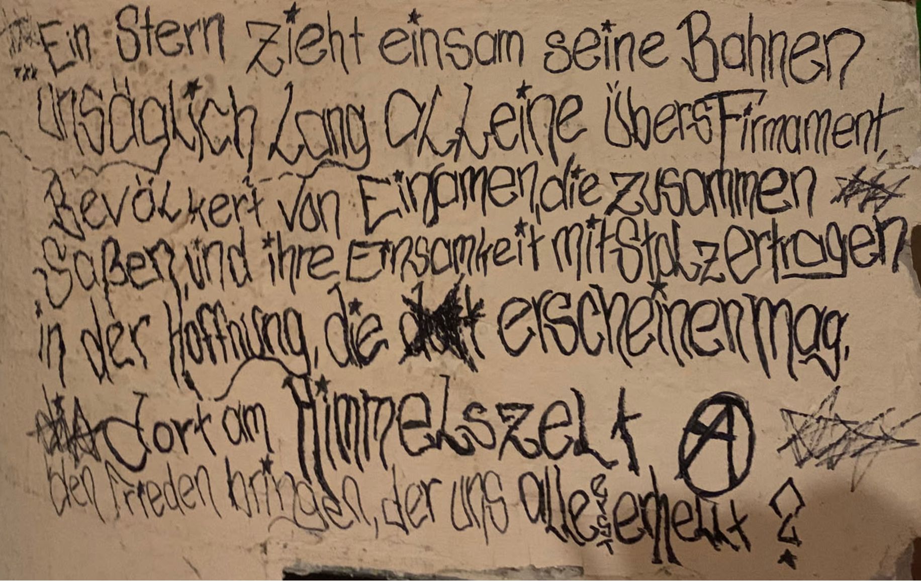 Eine Wand, auf der per Hand geschrieben steht:
Ein Stern zieht einsam seine Bahnen
unsäglich lang alleine übers Firmament
bevölkert von Einsamen, die zusammen
saßen, und ihre Einsamkeit mit Stolz ertragen
in der Hoffnung, die erscheinen mag,
dort am Himmelszelt
den Frieden bringen, der uns alle erst erhellt?