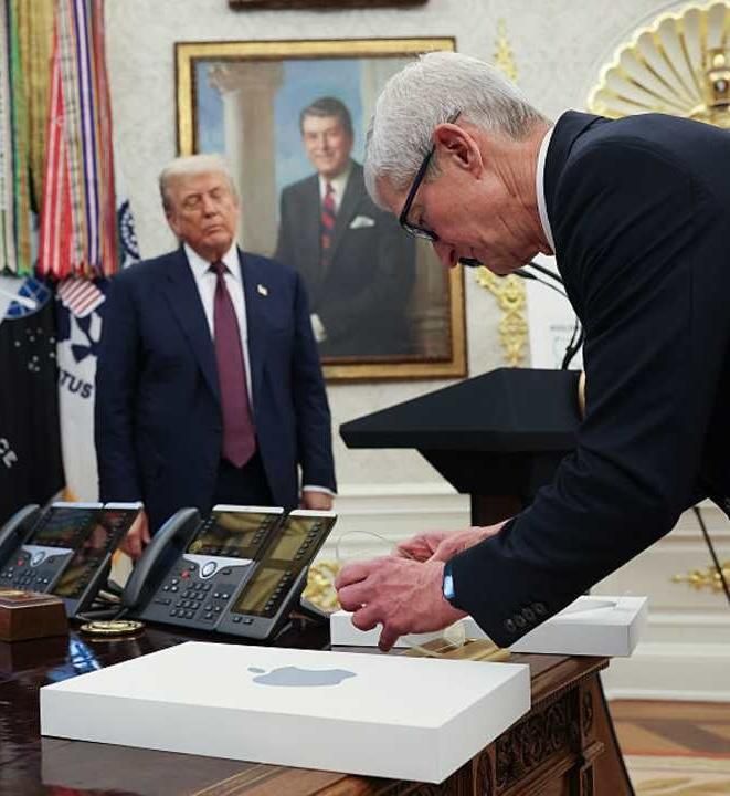 Tim Cook bowing to Trump as he presents a golden offering.